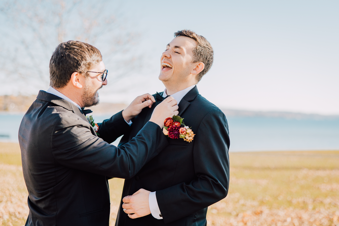 Groom laughs as his groomsman straightens his bowtie