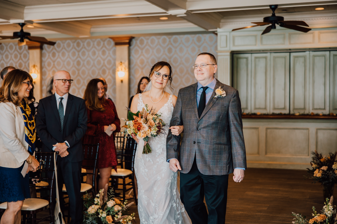 Bride smiles as she walks down the aisle at her country club wedding ceremony in Central NY