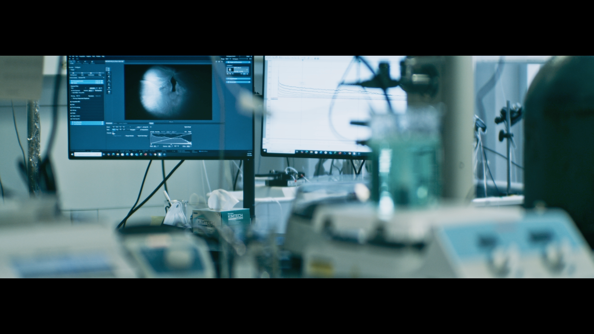 Medical laboratory with computer monitors displaying medical imaging and data, surrounded by scientific equipment