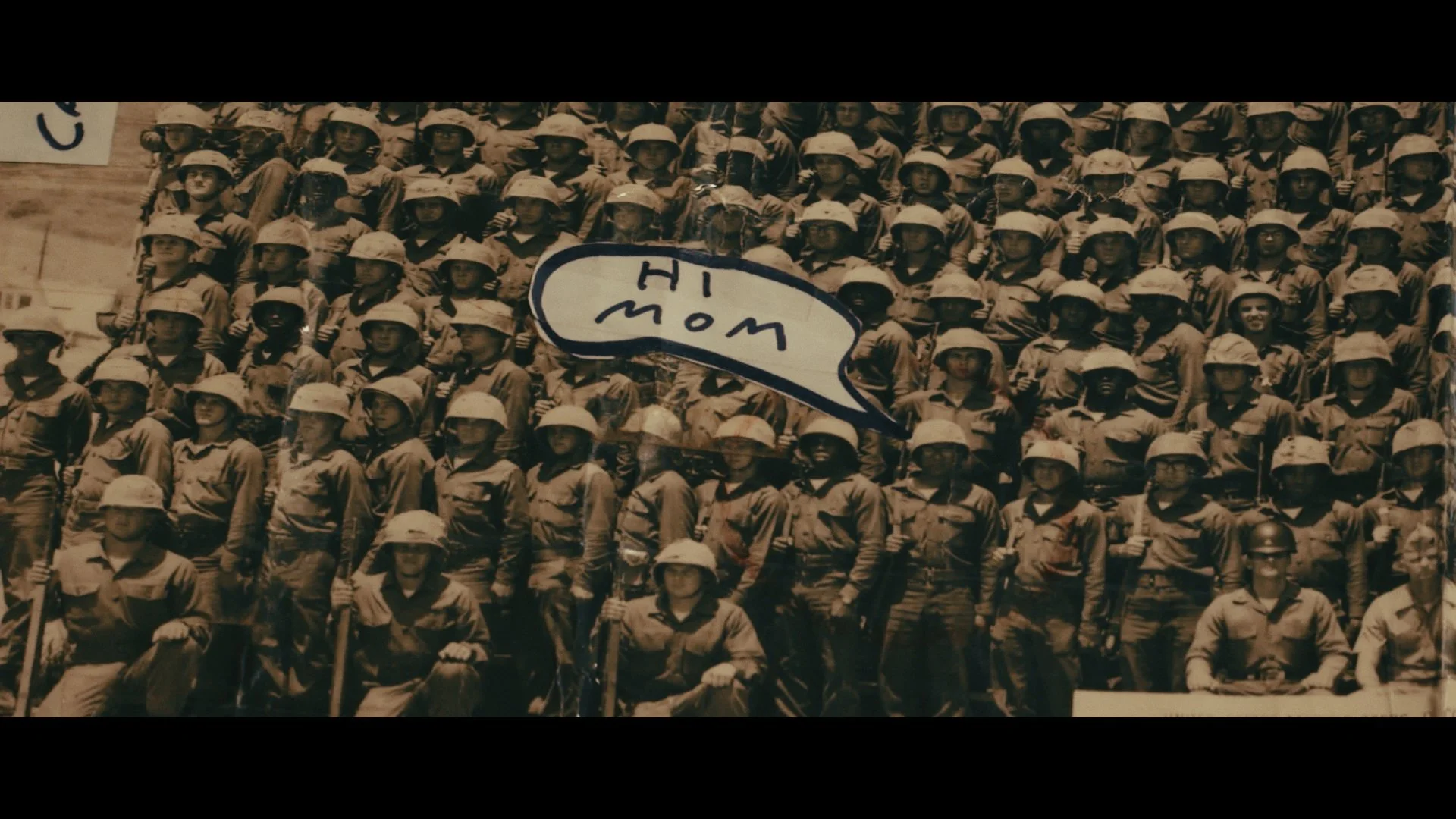 Historic black and white photo of soldiers in uniform with helmets, some holding rifles, with a speech bubble reading 'Hi Mom'.