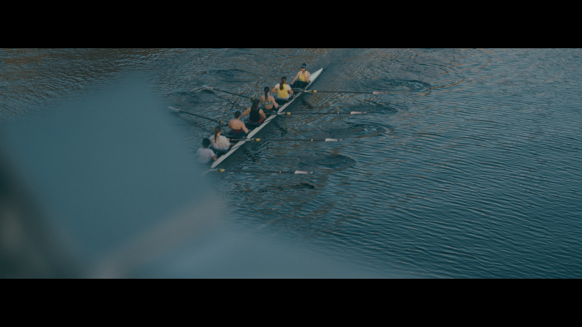A group of people rowing a boat in a river during daytime.