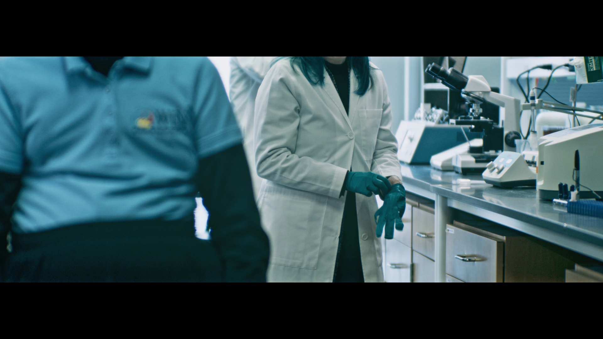 Scientists in a laboratory working with scientific equipment, including microscopes and lab instruments.