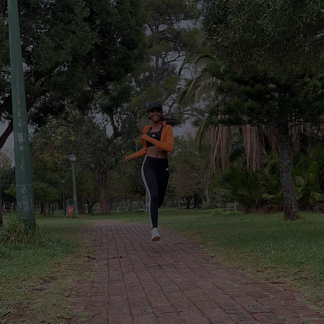 Bridgette running at De Waal Park in her Adidas gear, smiling on a cloudy day in Cape Town.