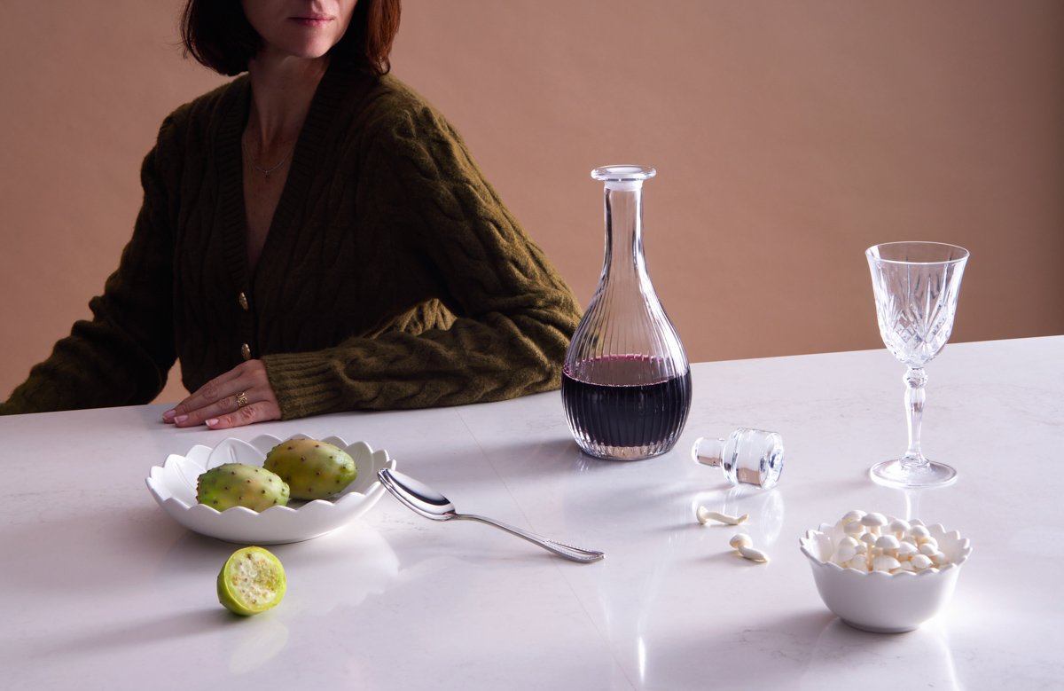 Moody interior shot of a dining table styled with a decanter, crystal glasses, and limes, by Bakkes Images.