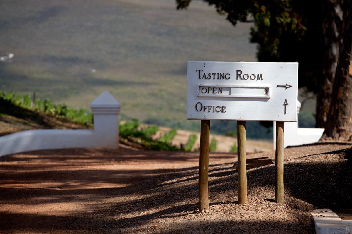 A rustic wooden directional sign post pointing toward the Hamilton Russell tasting room, by Bakkes Images.