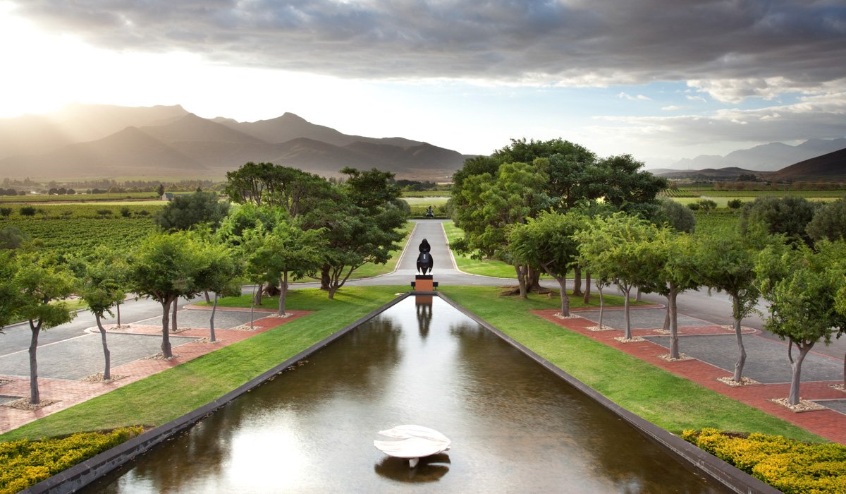 A large symmetrical modern reflecting water feature leading toward mountains at Graham Beck, by Bakkes Images.