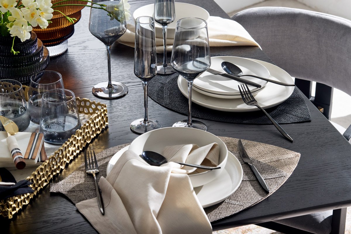 A close-up look at sophisticated monochromatic table settings with gold flatware details, by Bakkes Images.