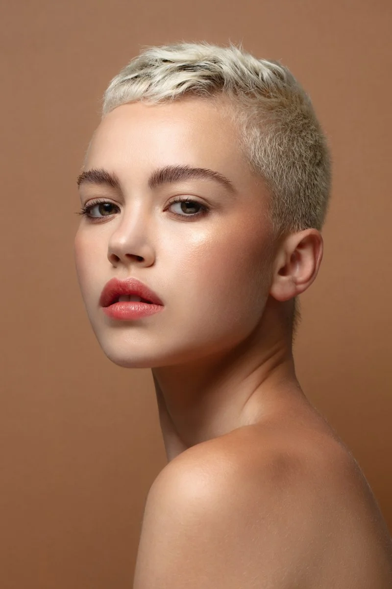 Clean minimalist studio beauty profile showcasing clean skin textures on a warm beige backdrop, by Bakkes Images.