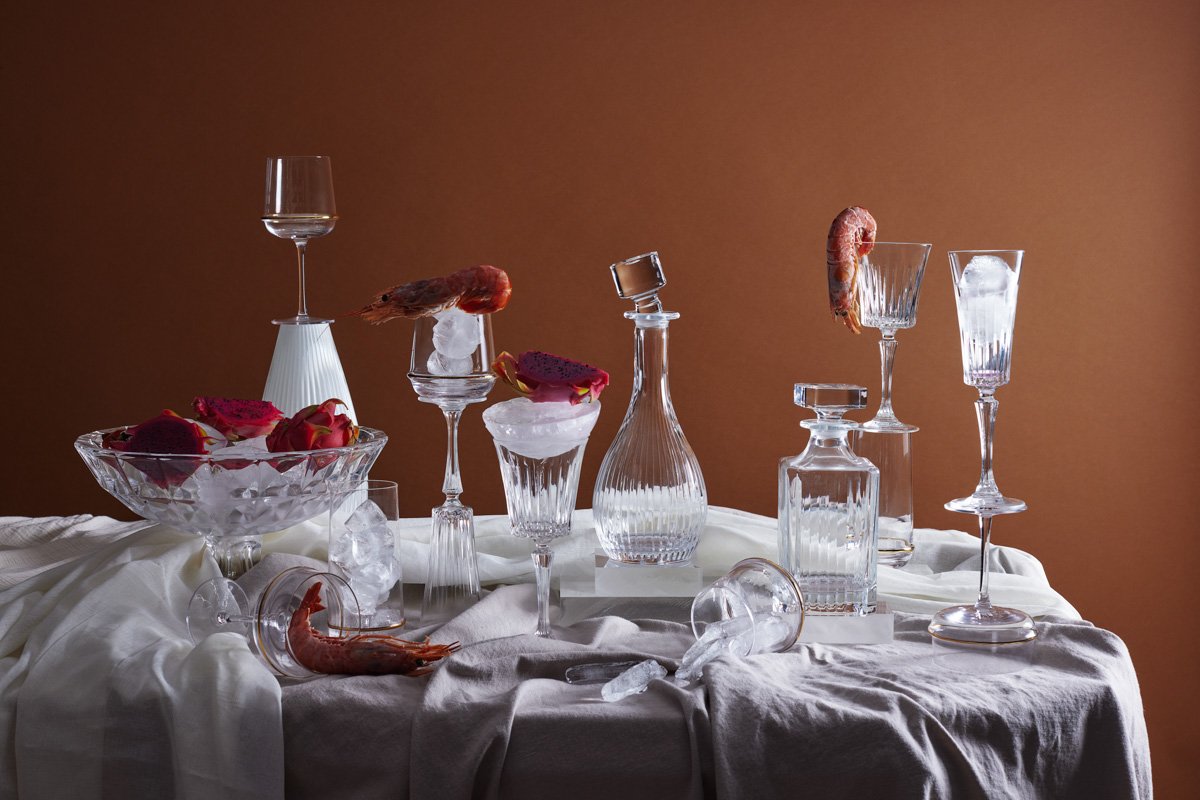 An elegant dining table spread featuring assorted crystal glassware, wine decanters and candles, by Bakkes.
