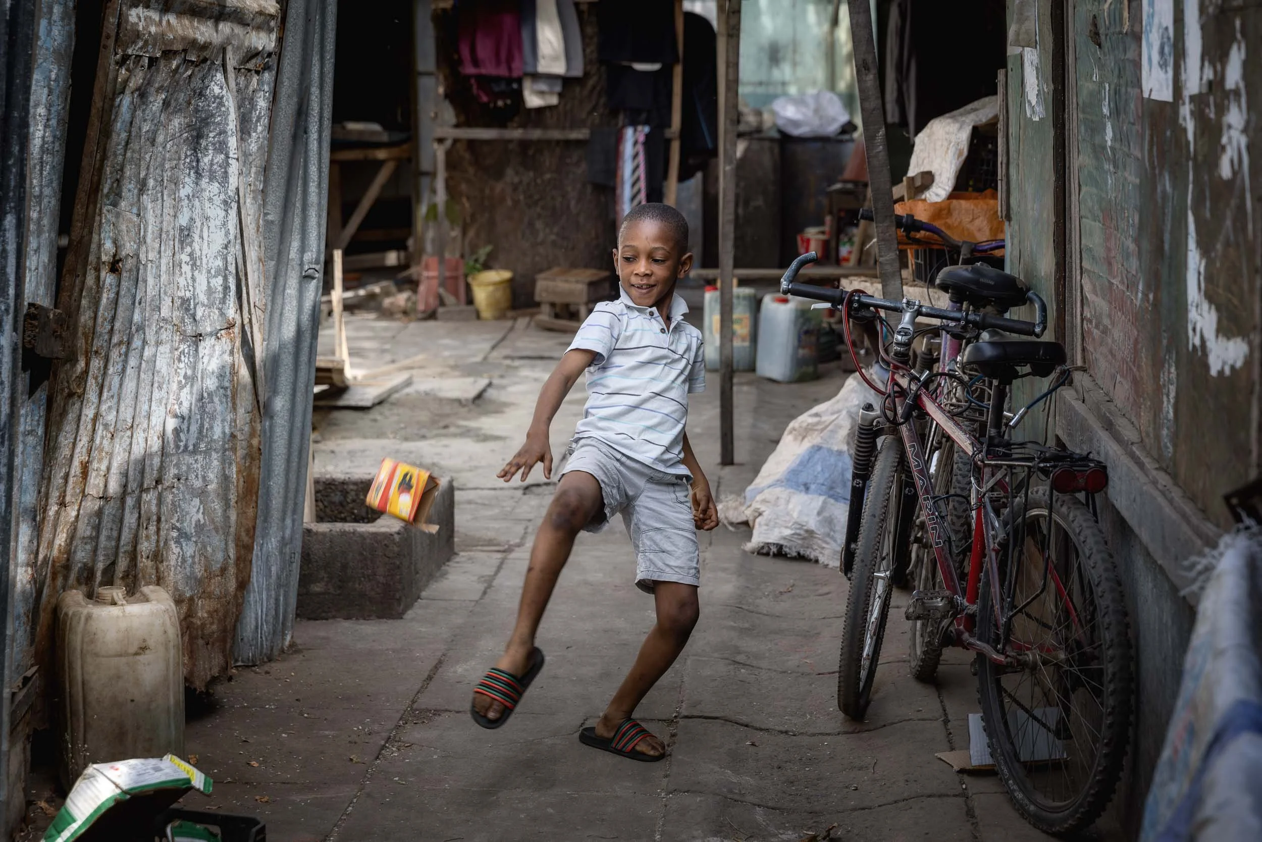 Boy kicking a box in street, Gambia