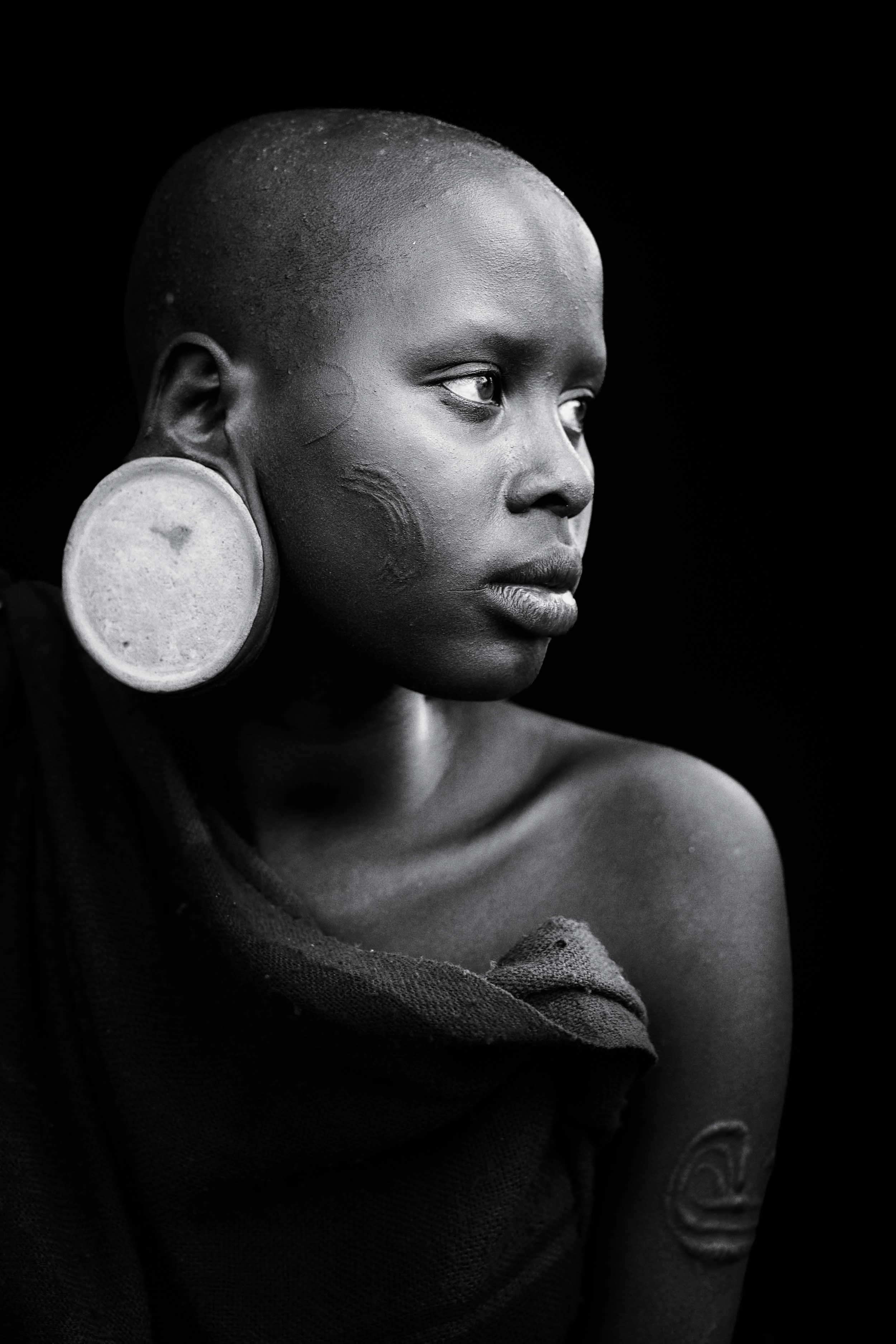 Suri girl with scarification and traditional earrings, Ethiopia