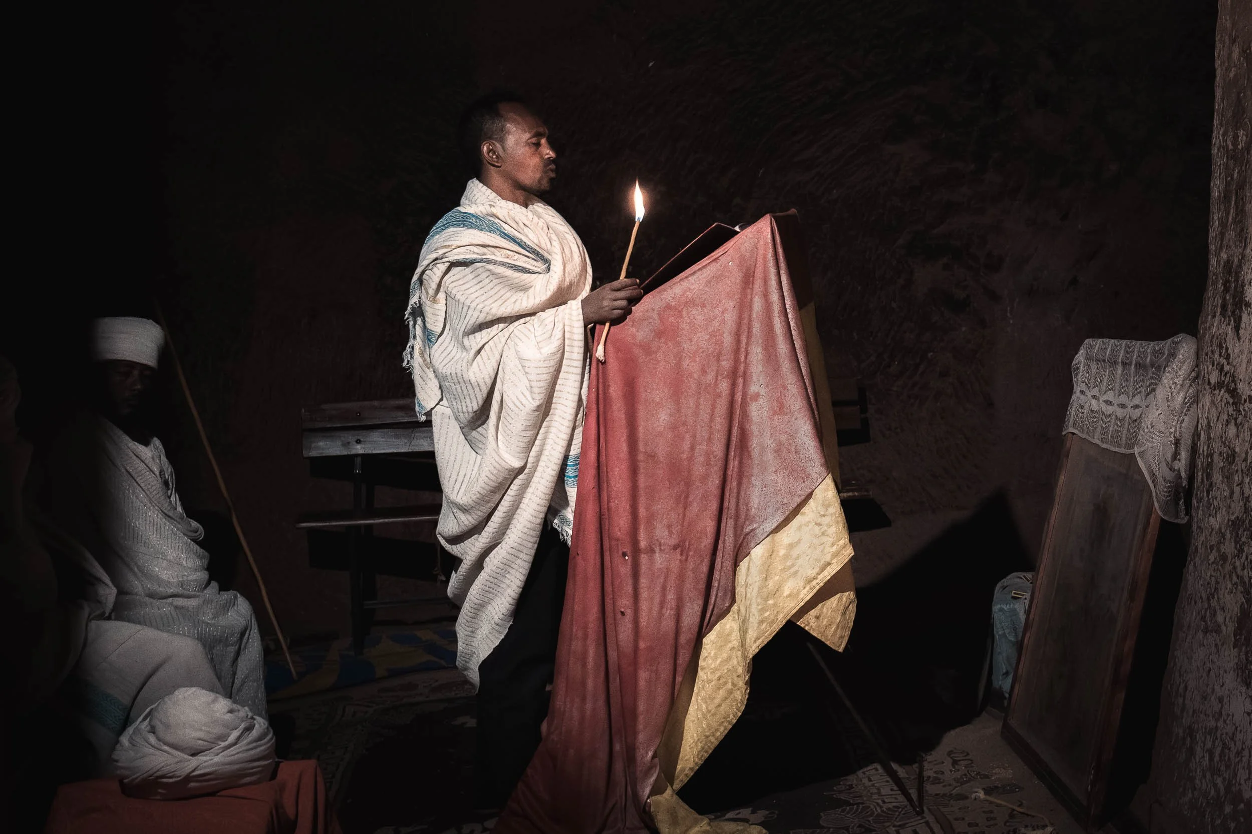Priest holding candle in dark church, Lalibela, Ethiopia