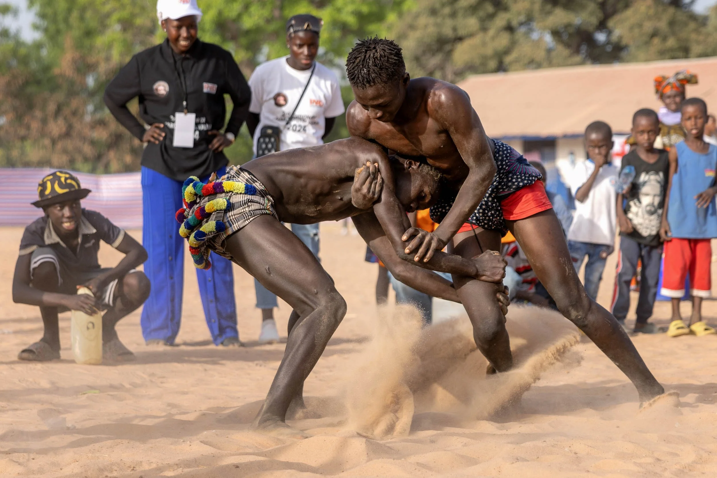 Two men wrestling in sand, Gambia