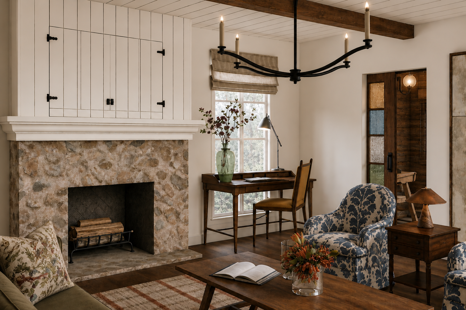 A cozy living room with a stone fireplace, wooden ceiling beams, an armchair with floral fabric, a wooden side table with a lamp, a small wooden writing desk with a green vase and flowers, a window with beige curtains, and a chandelier with candles.