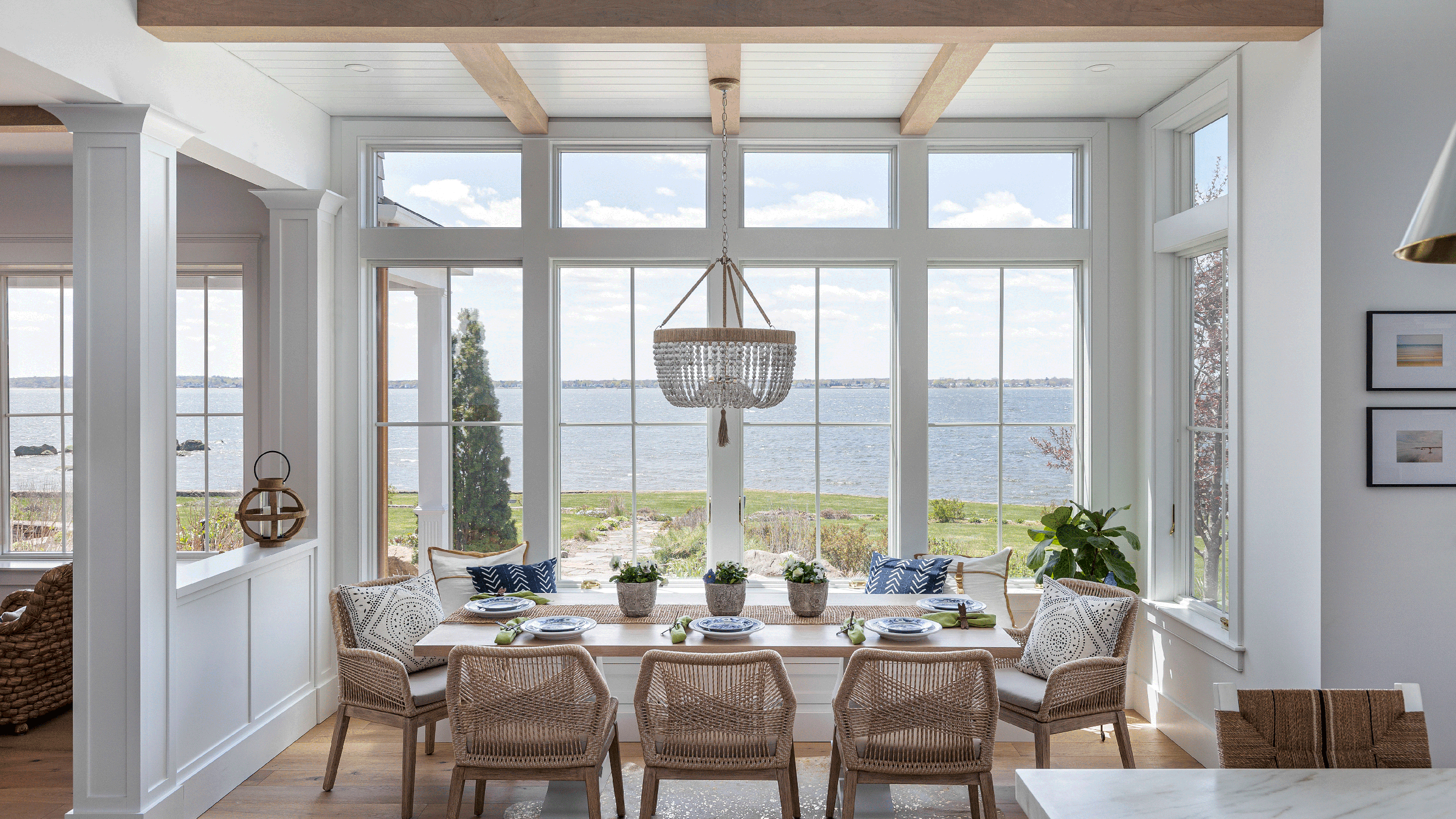 Casual dining with a water view; Woven dining chairs and beaded chandelier. 