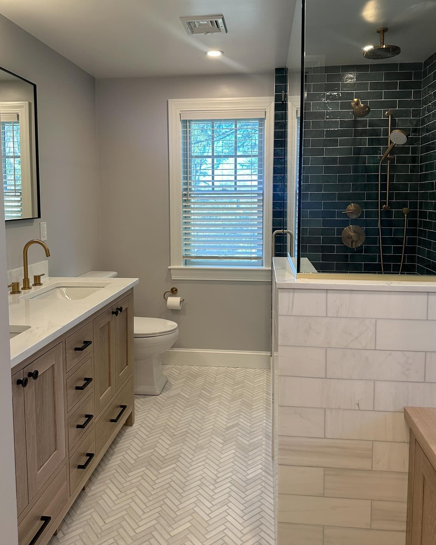 This primary bathroom renovation looks beautiful! We love the finishes Laura and our client selected, especially the green tile from @bedrosianstile. It coordinates so well with the marble herringbone tile and the oil-rubbed bronze fixtures. The whit