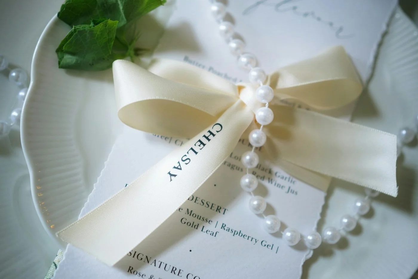 Elegant rehearsal dinner menu and place setting with ribbon and pearls