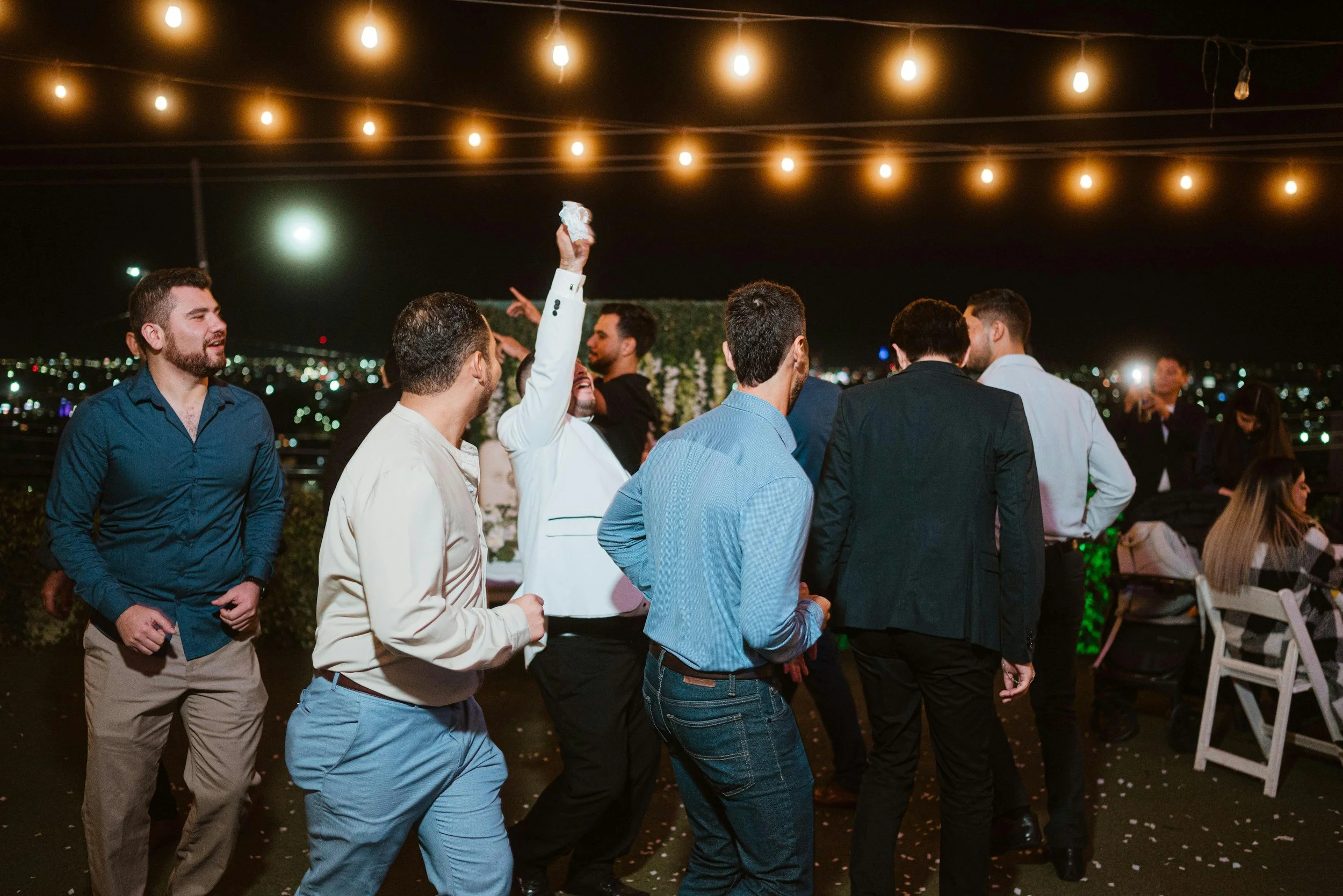 Wedding guests dancing beneath warm string lights at an evening reception