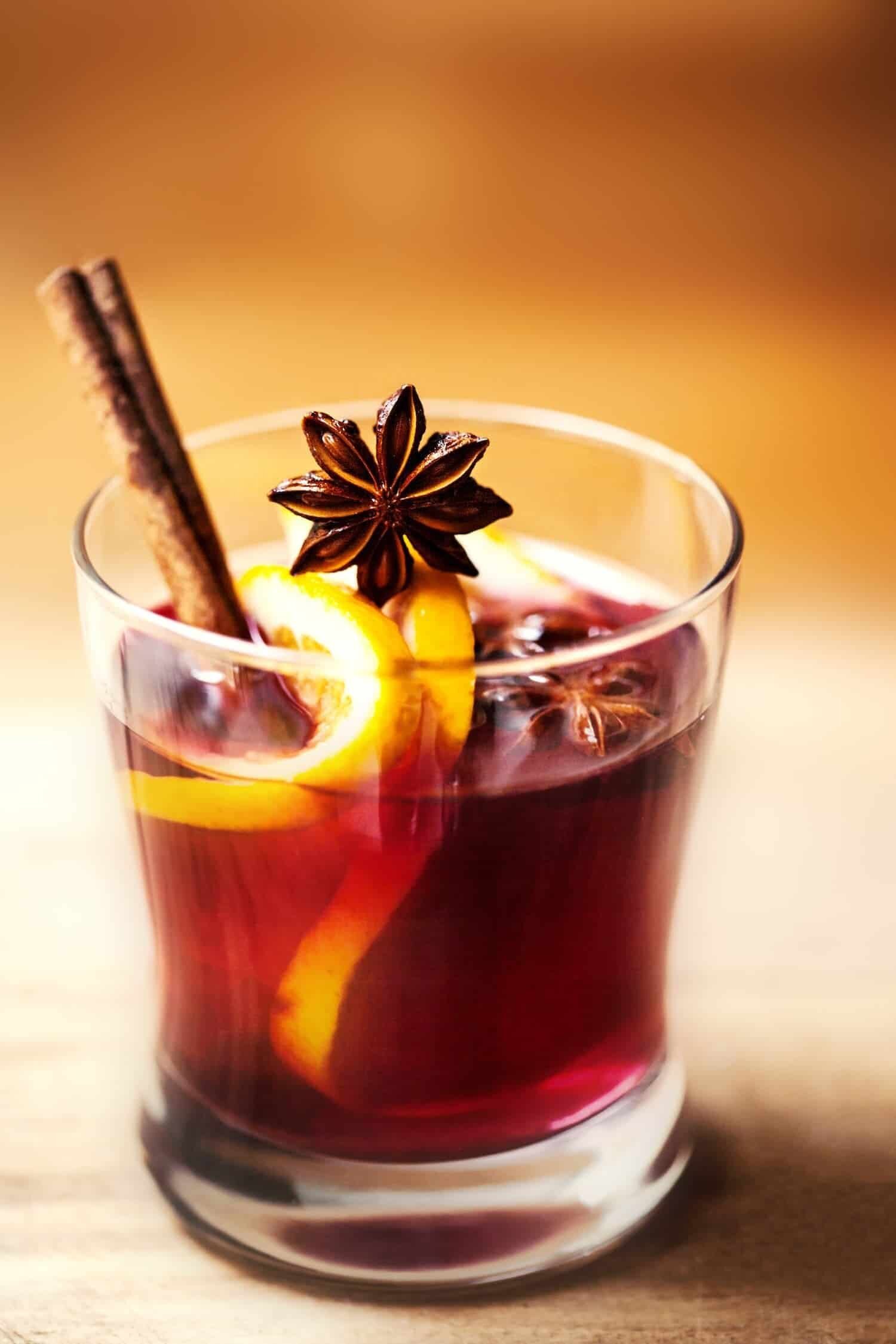 Glass of mulled wine with lemon slices and spices.