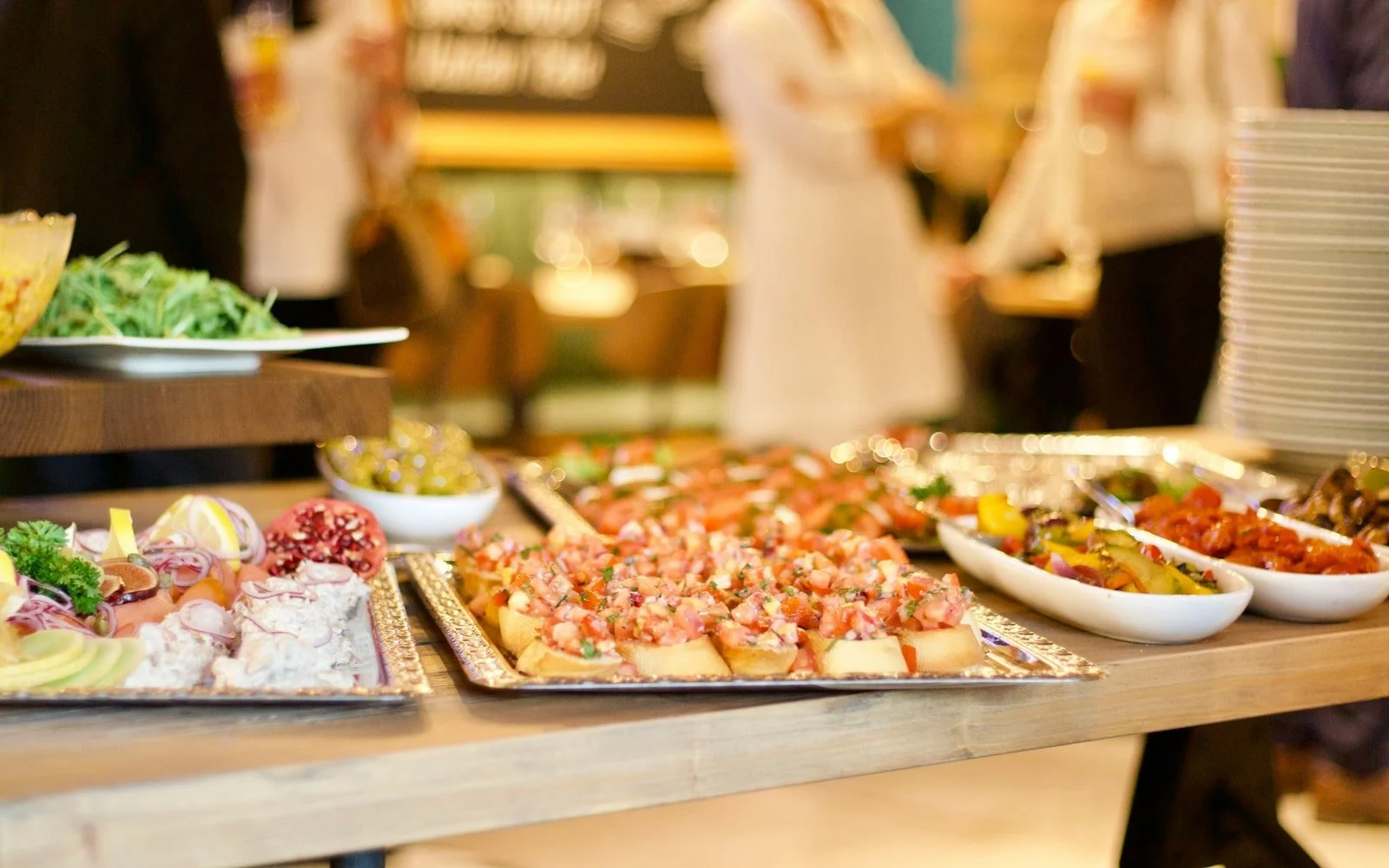 Wedding buffet tables with catered dishes and staff preparing service