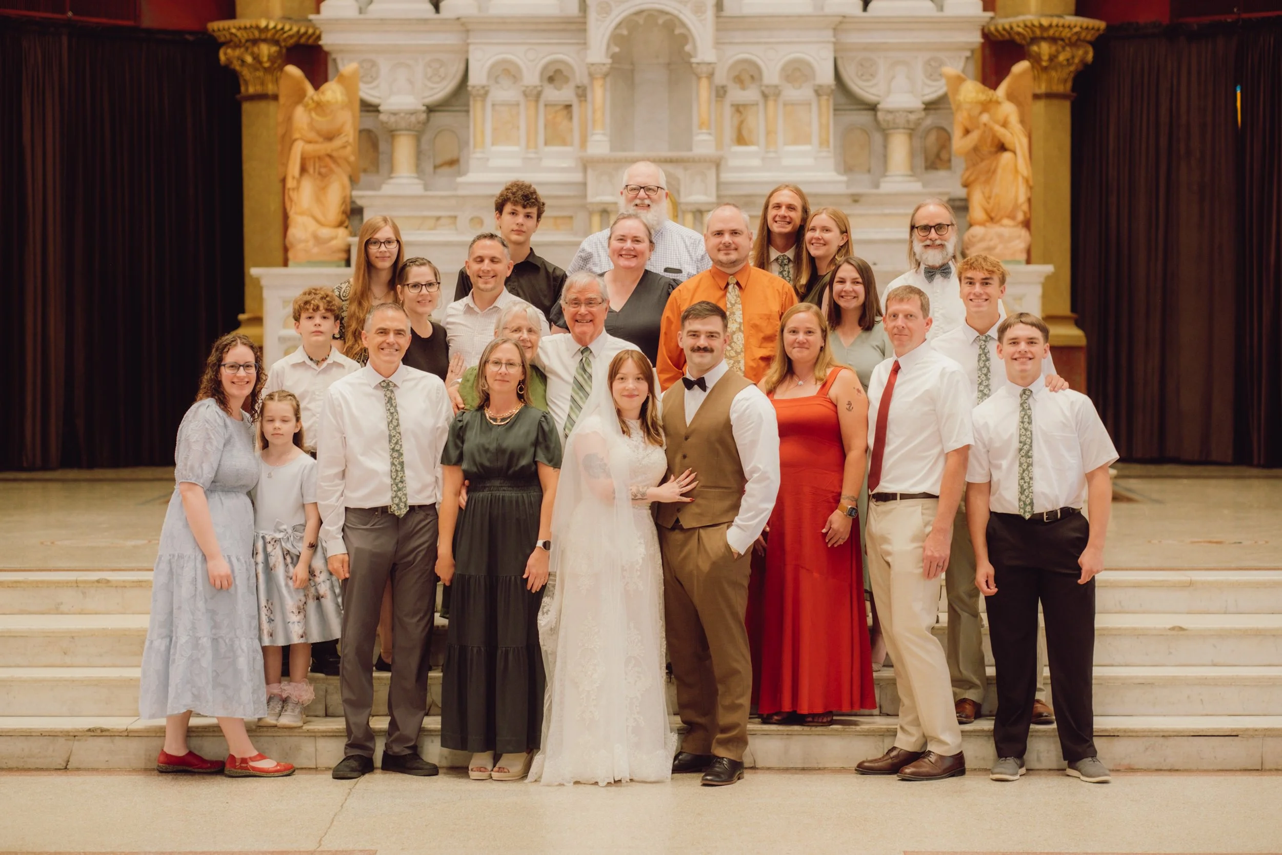 Group of people at a wedding celebration, standing on the steps of a church altar.