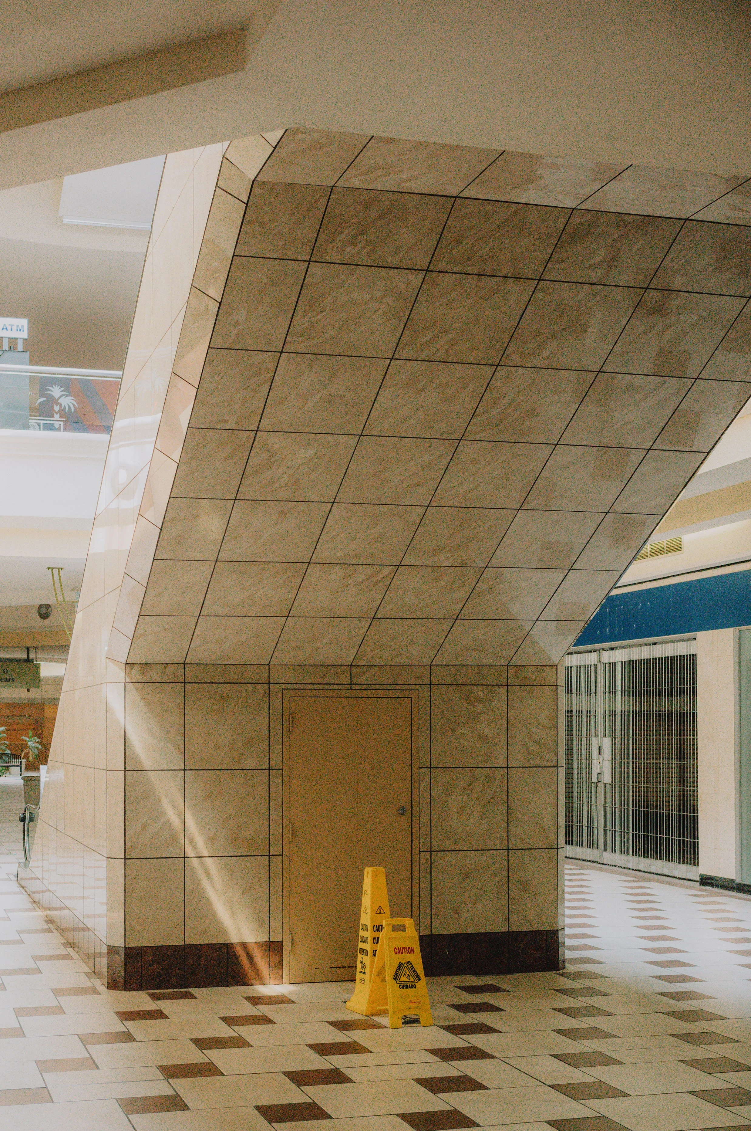 Indoor shopping mall with tiled floor, tiled structure, and a caution wet floor sign.