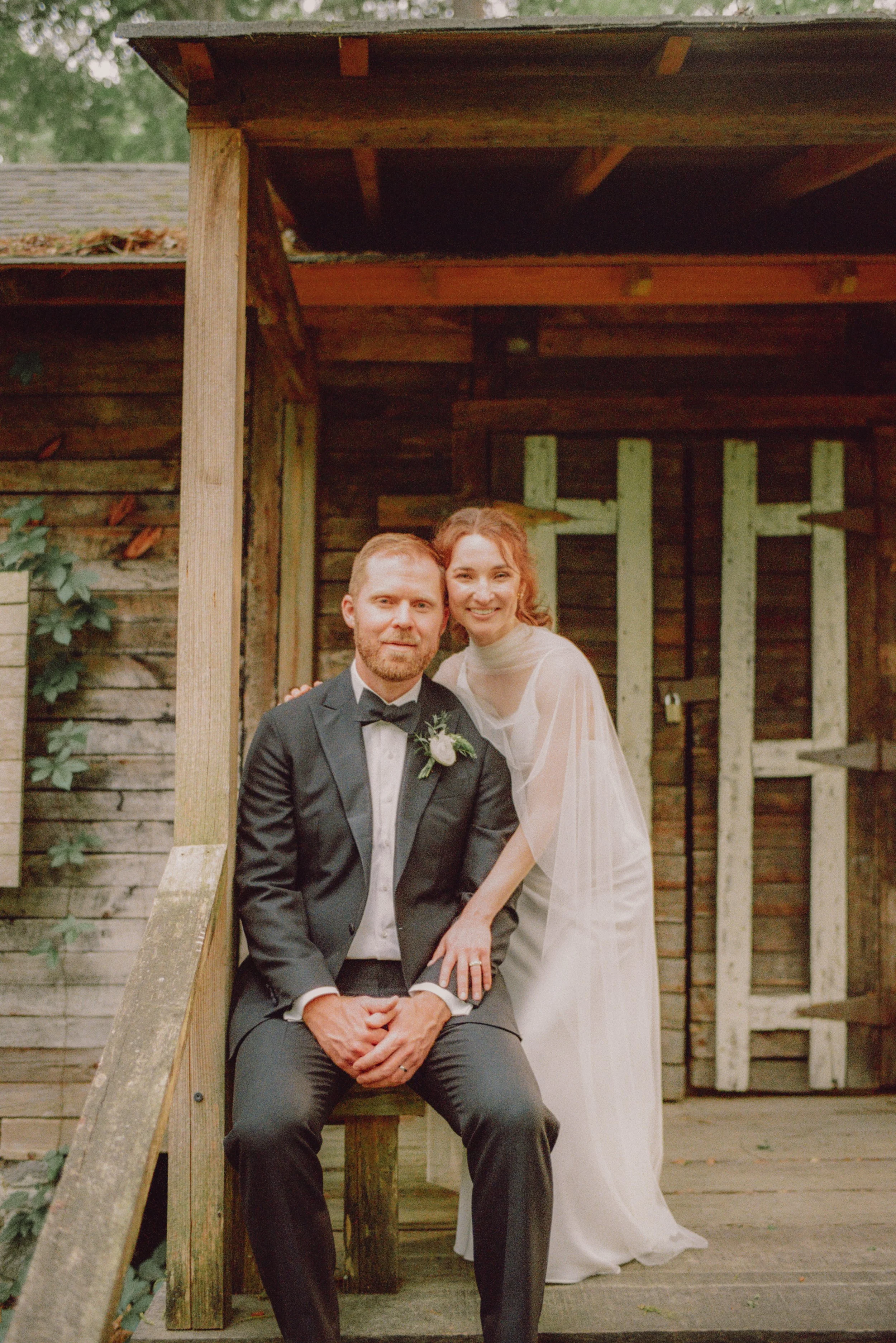 Bride and groom sitting together on the steps of a rustic wooden cabin porch at the Museum of Arts and Sciences