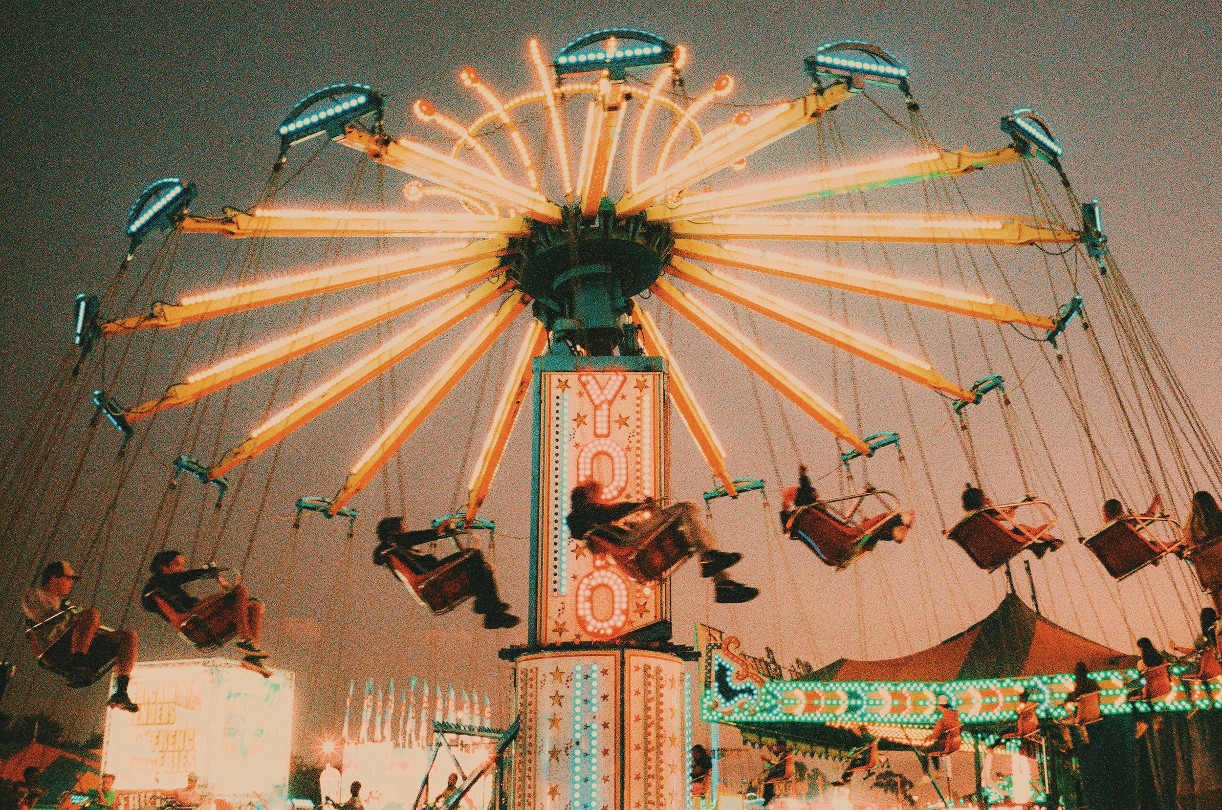 a state fair ride with children swinging and bright lines shining on film. Lomography 800.