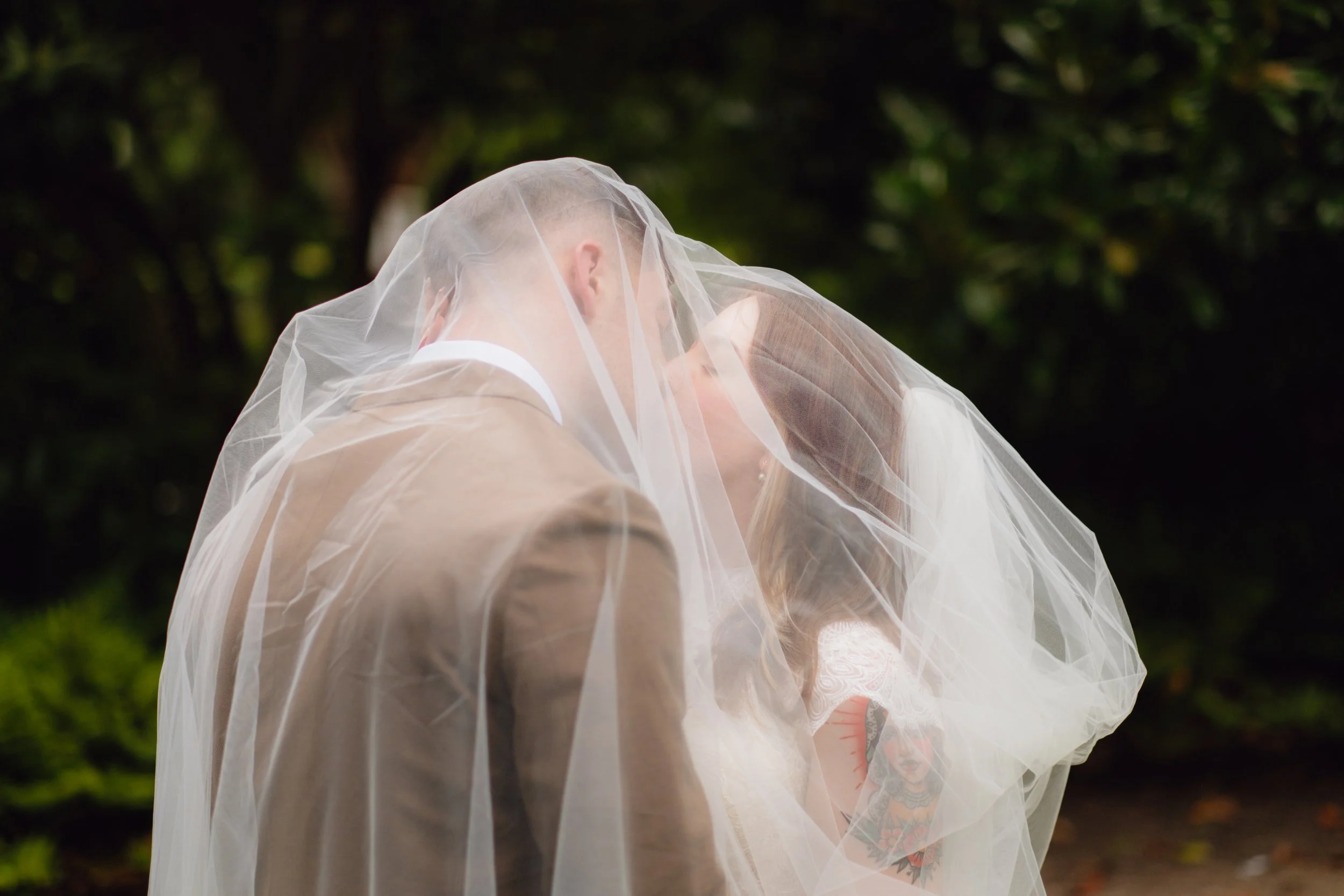 Bride and groom kiss under a veil in the courtyard at Sacred Heart Cultural Center in Augusta, Georgia