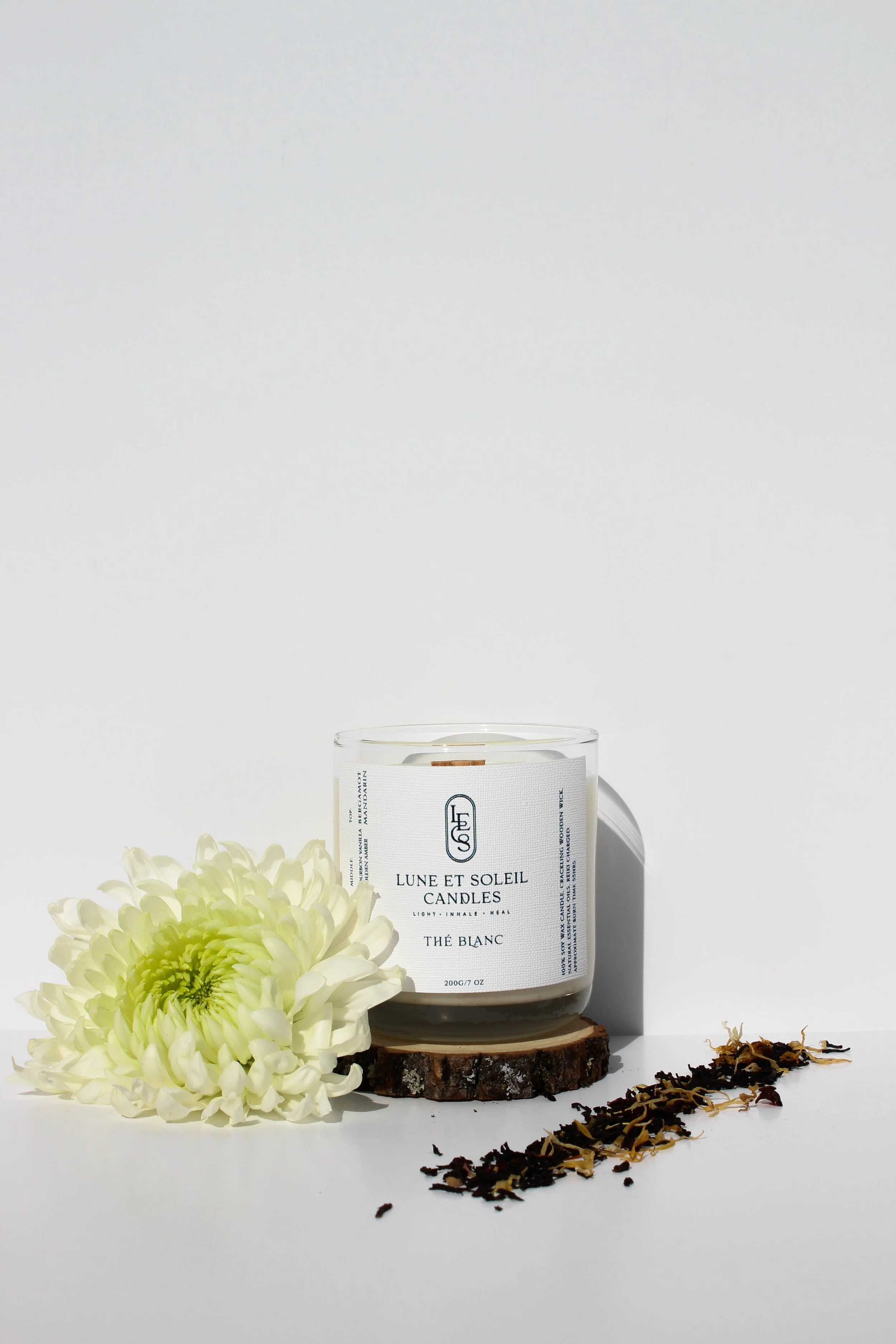 Thé Blanc soy wax candle in a clear glass vessel styled with a white flower by Lune et Soleil