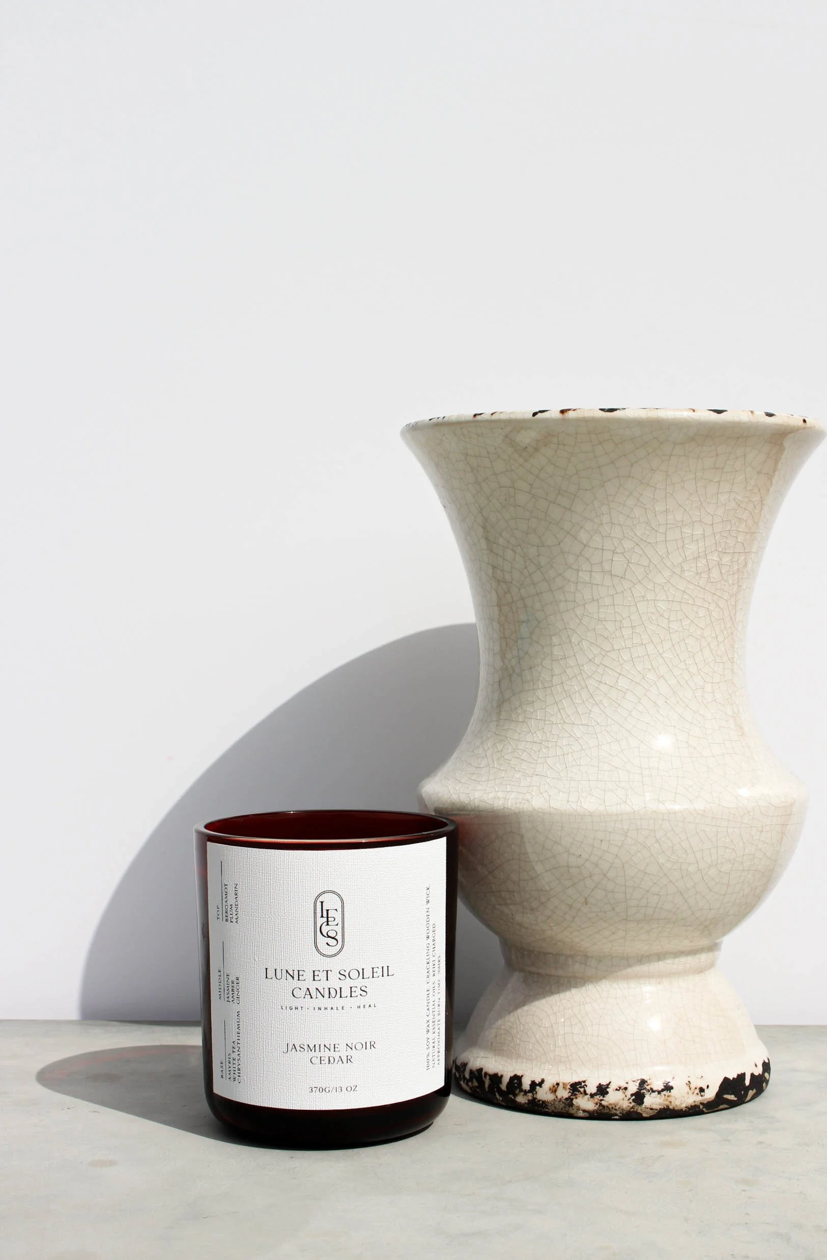 Jasmine Noir Cedar soy candle in a dark red vessel styled with a vase by Lune et Soleil