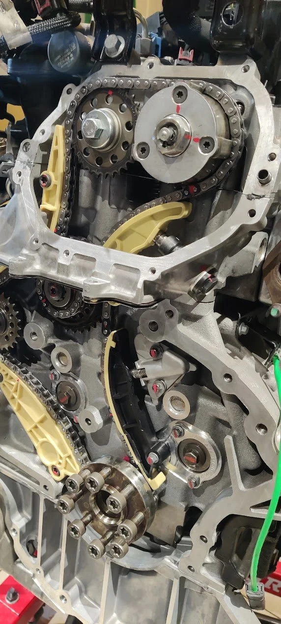 Close-up of an internal engine part showing camshafts, chains, and valves.