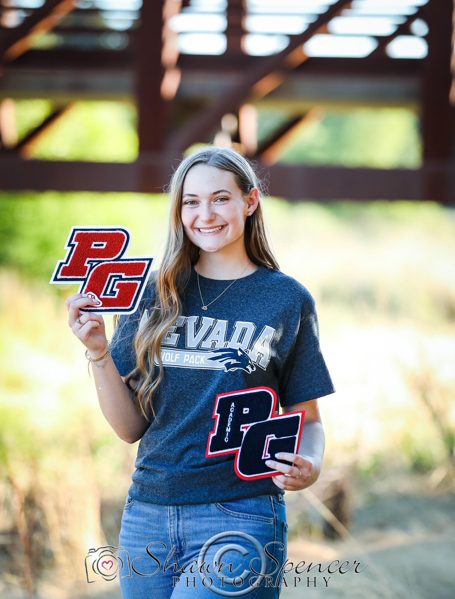  senior girl standing wearing college acceptance t-shirt holding high school letters 