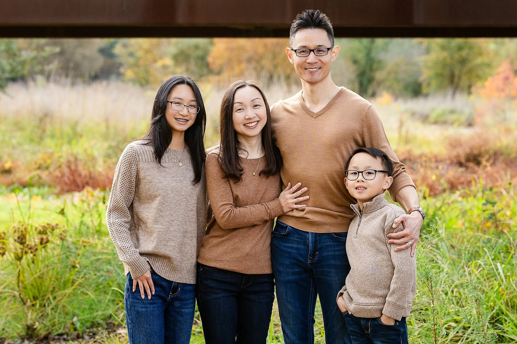 A family wearing neutral, coordinated outfits during an outdoor family photo session at Jack Hill Park in Elk Grove, California