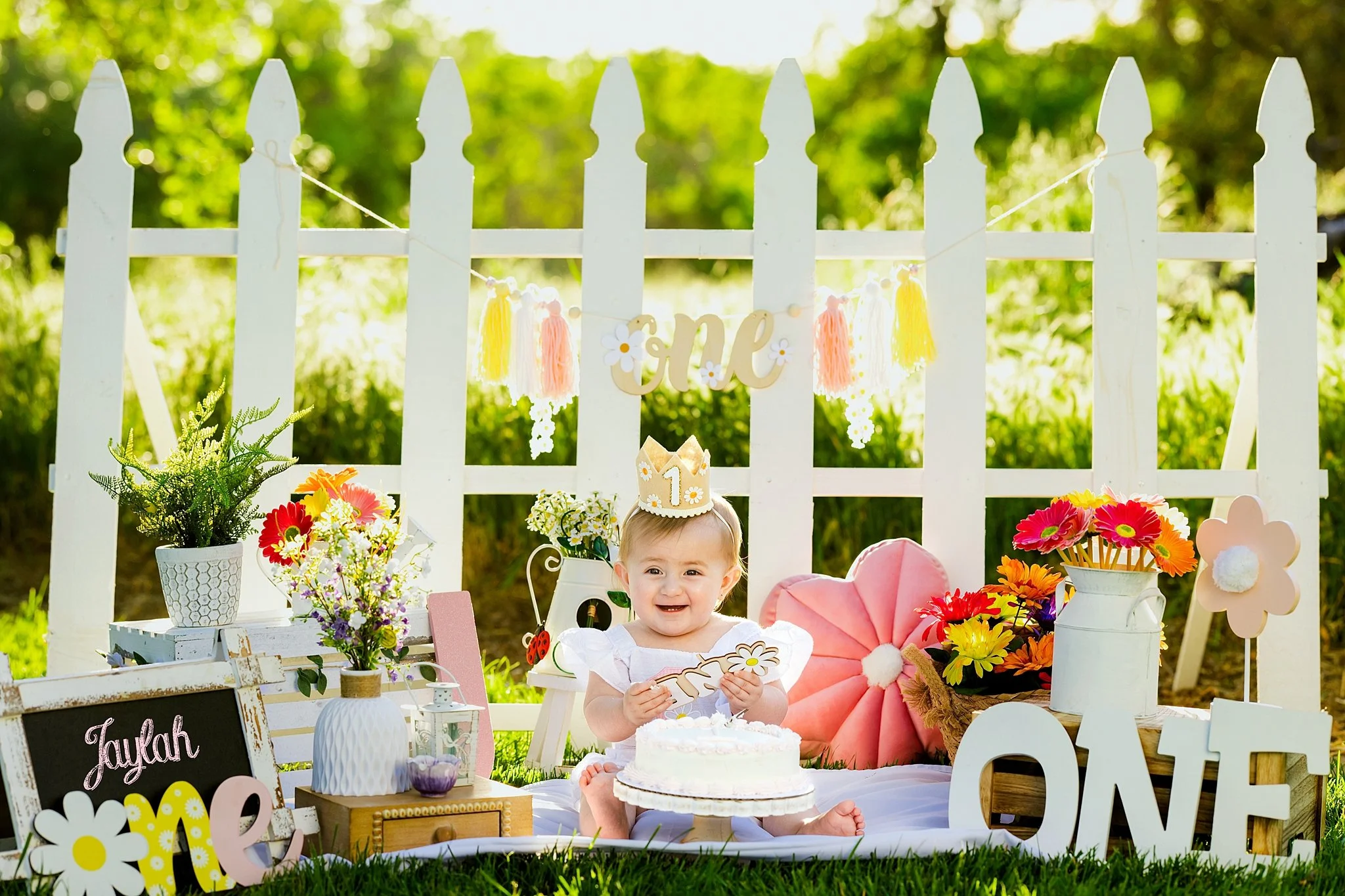 One-year cake smash session with white picket fence backdrop and daisy decor photographed in Elk Grove, CA.