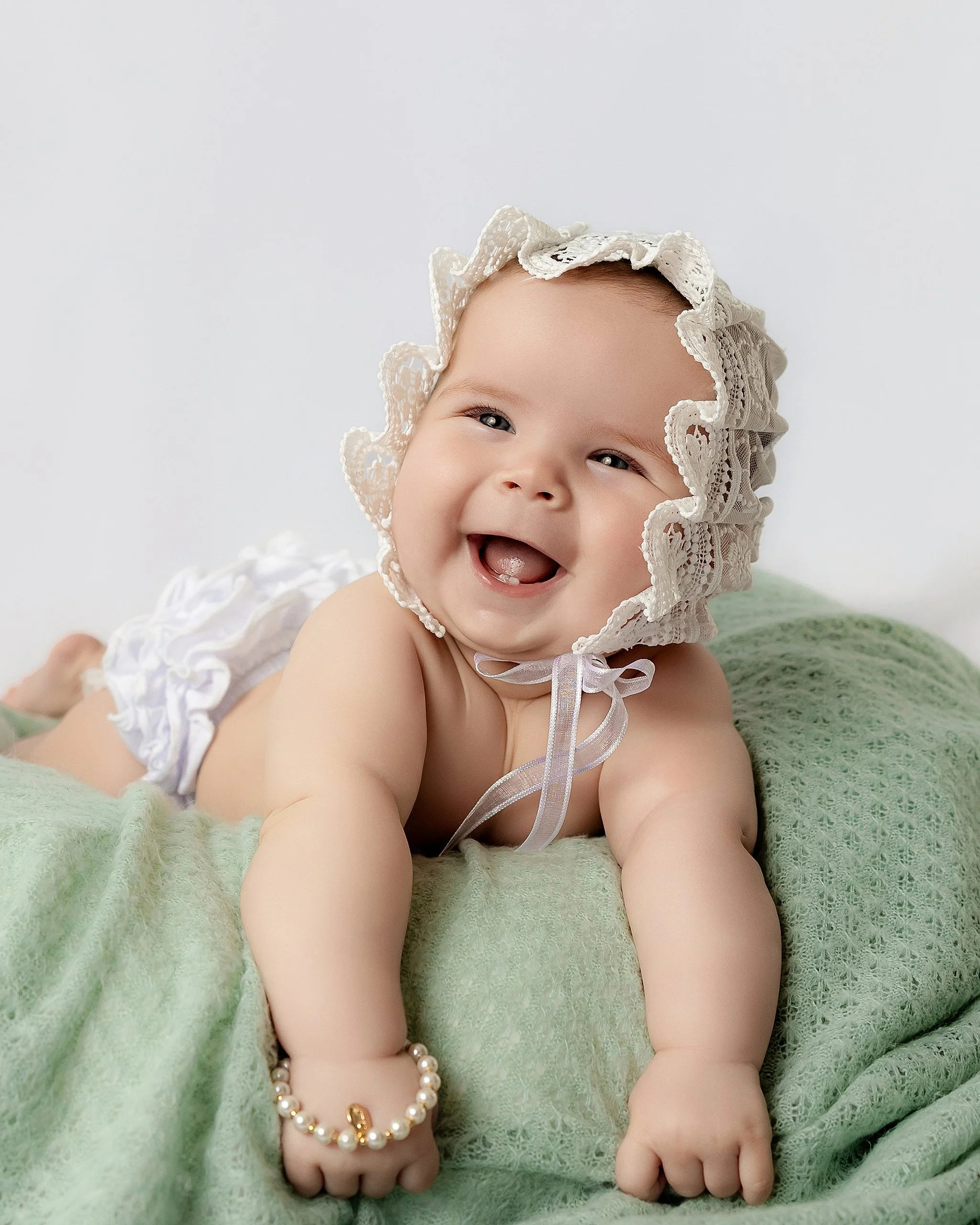 Smiling six-month-old baby girl during a tummy time milestone portrait in Shawn Spencer Photography's Elk Grove studio