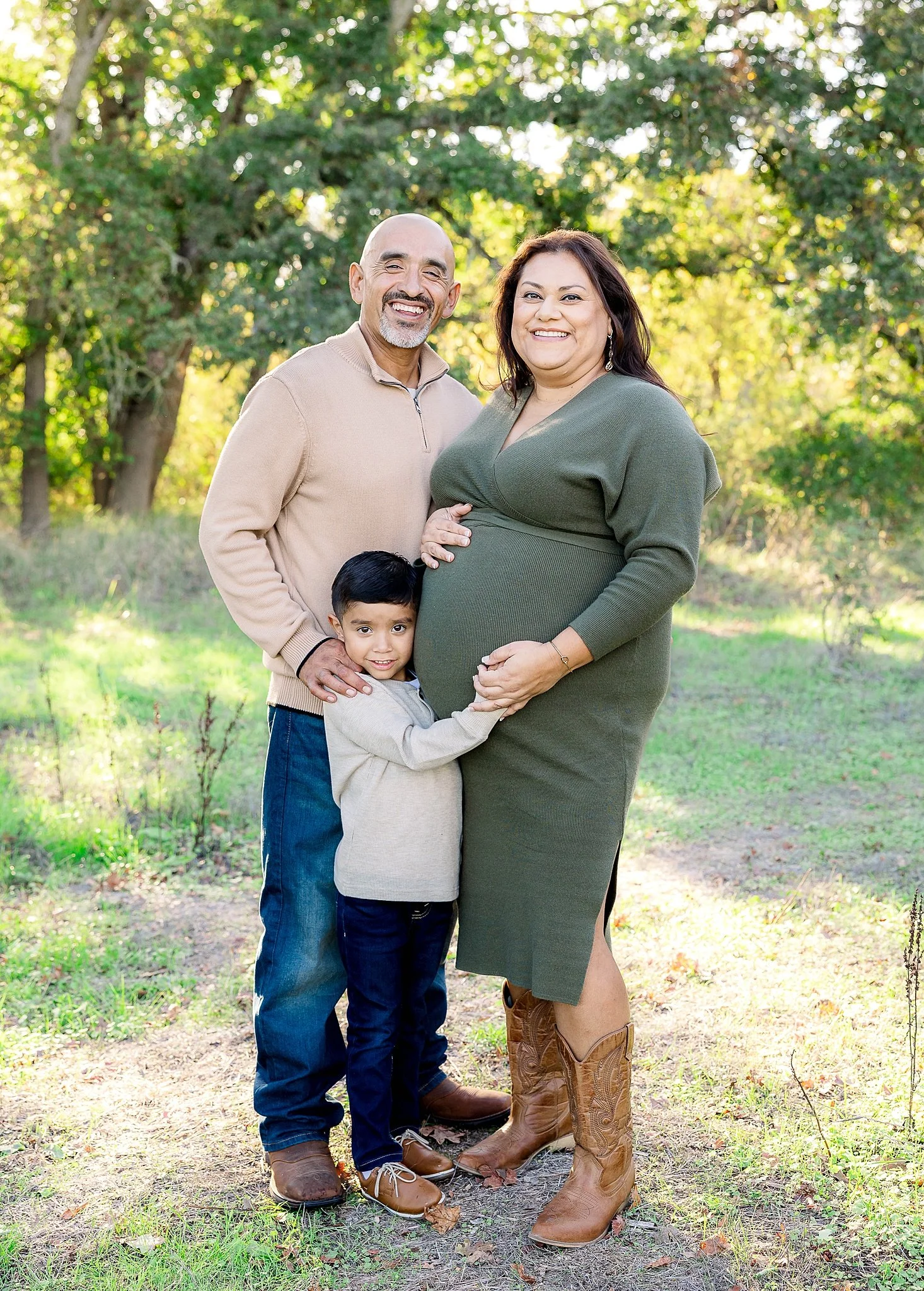 Family maternity portrait outdoors in Elk Grove, California with expecting parents and their young son hugging mom’s baby bump