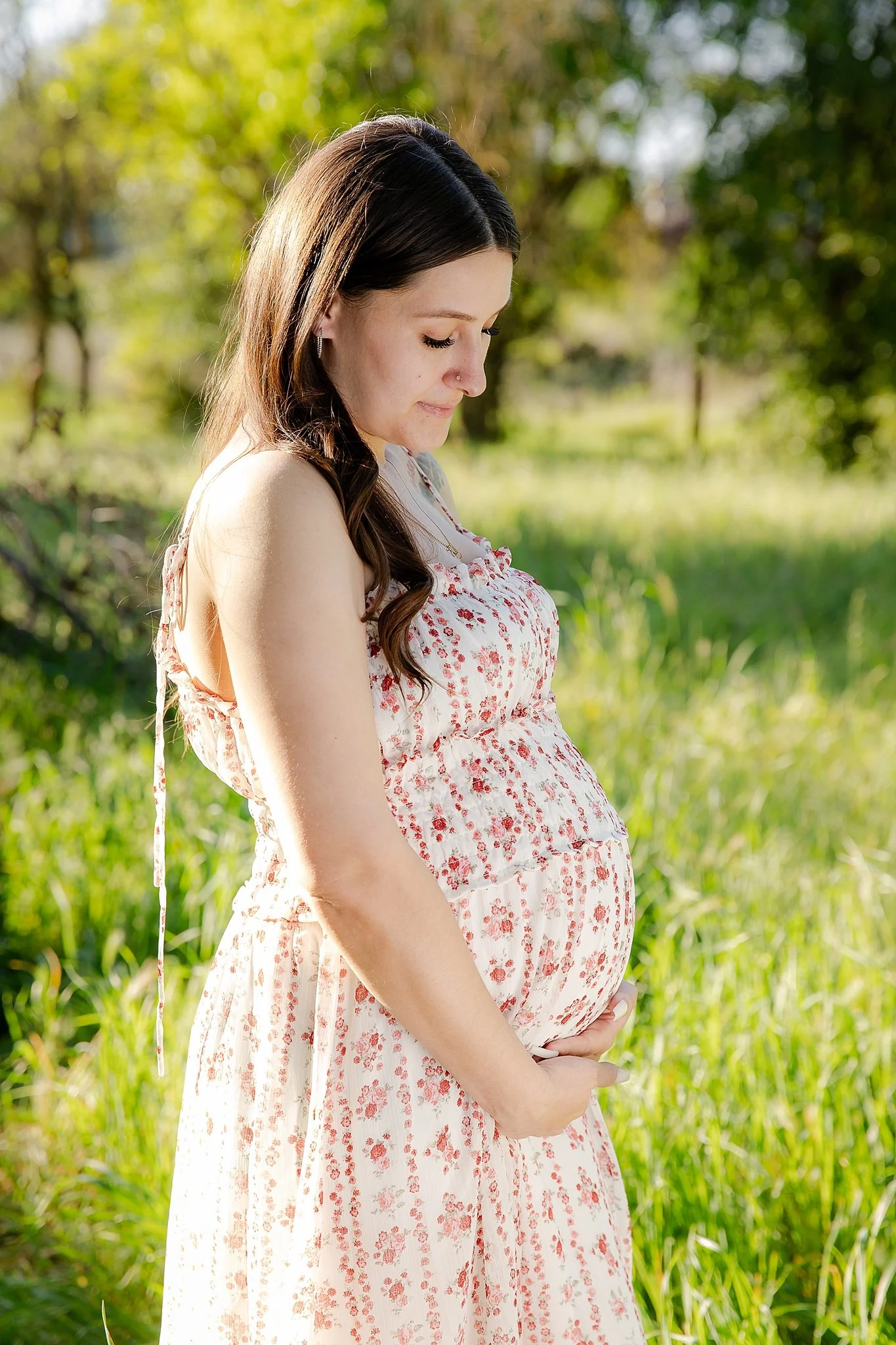 Natural maternity portrait of an expecting mother gently holding her baby bump during an outdoor session in Elk Grove, California