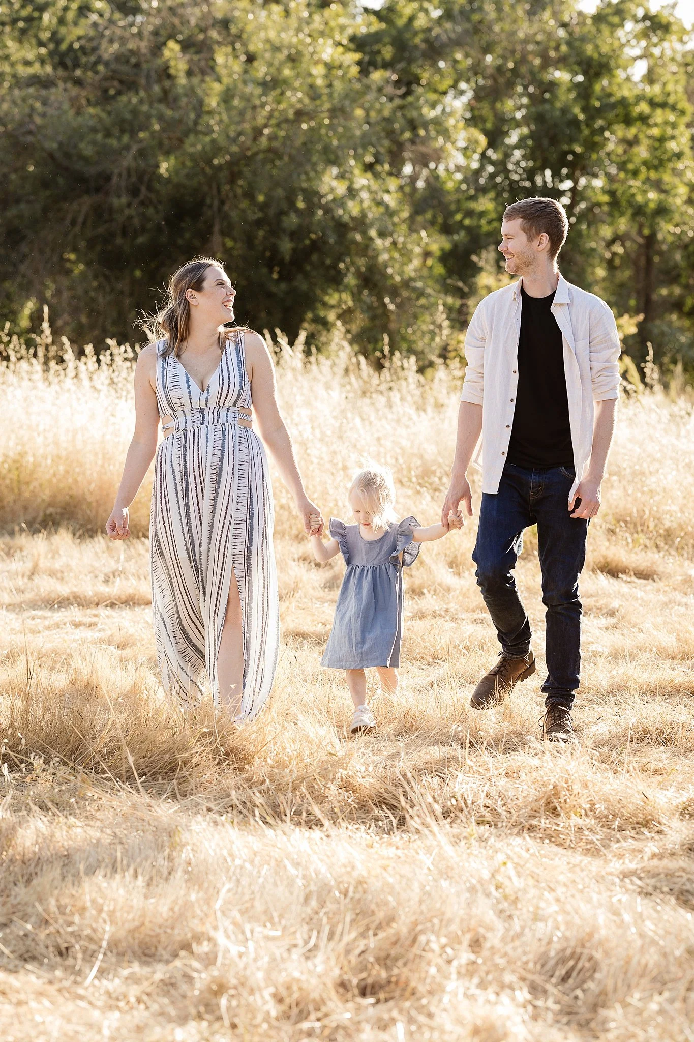 Smiling family in casual clothes, relaxed and laughing during a photo session outdoors.