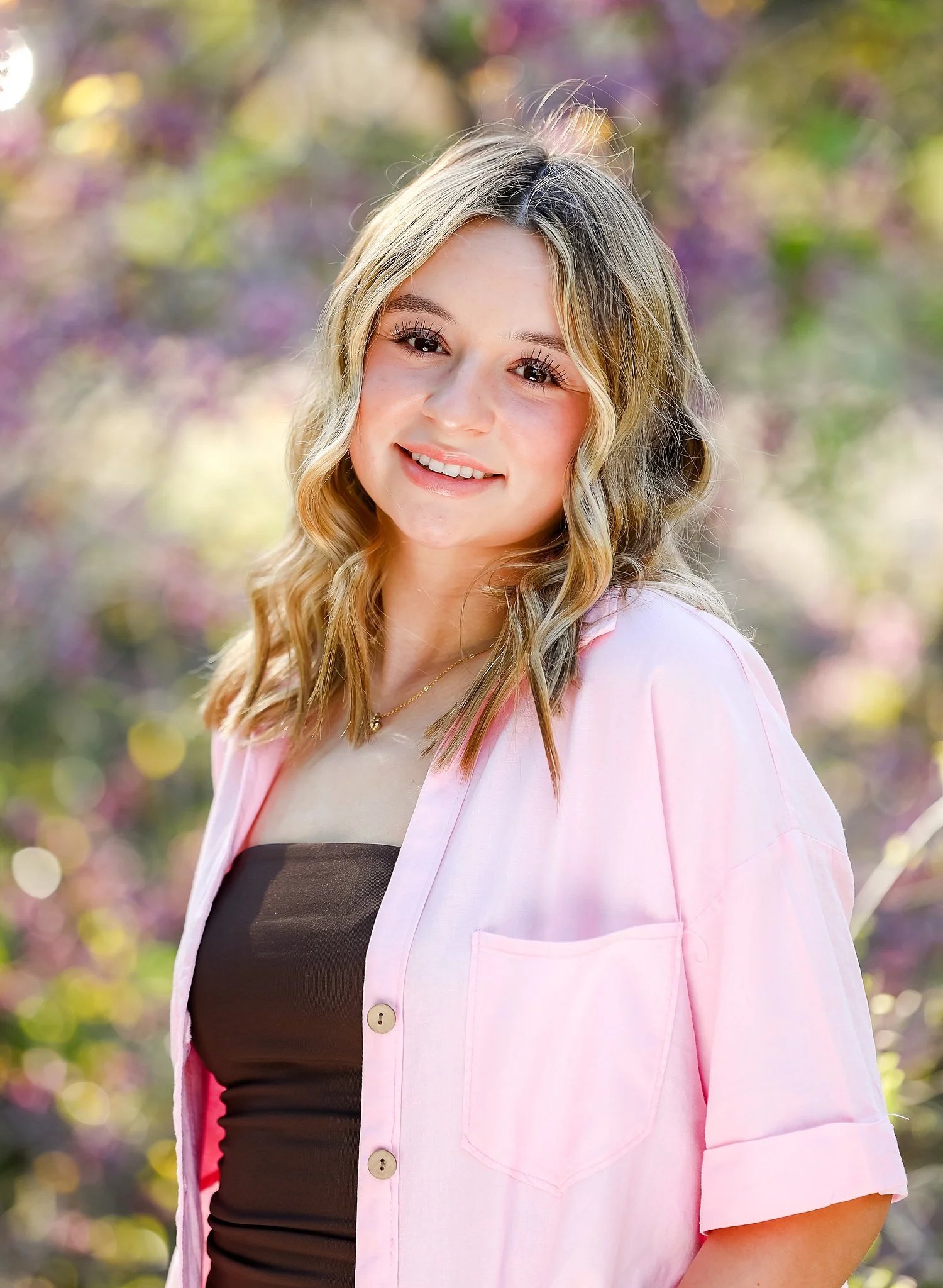 Teenage girl wearing brown tank top with pink shirt over and clean minimal makeup and hair look.