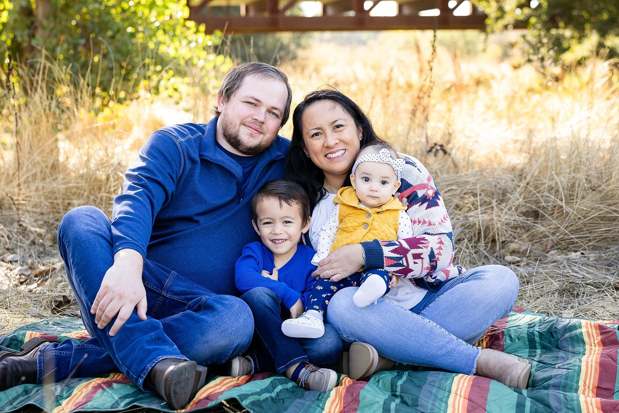 A family sitting together on a blanket during a relaxed outdoor family photo session at Jack Hill Park in Elk Grove, California