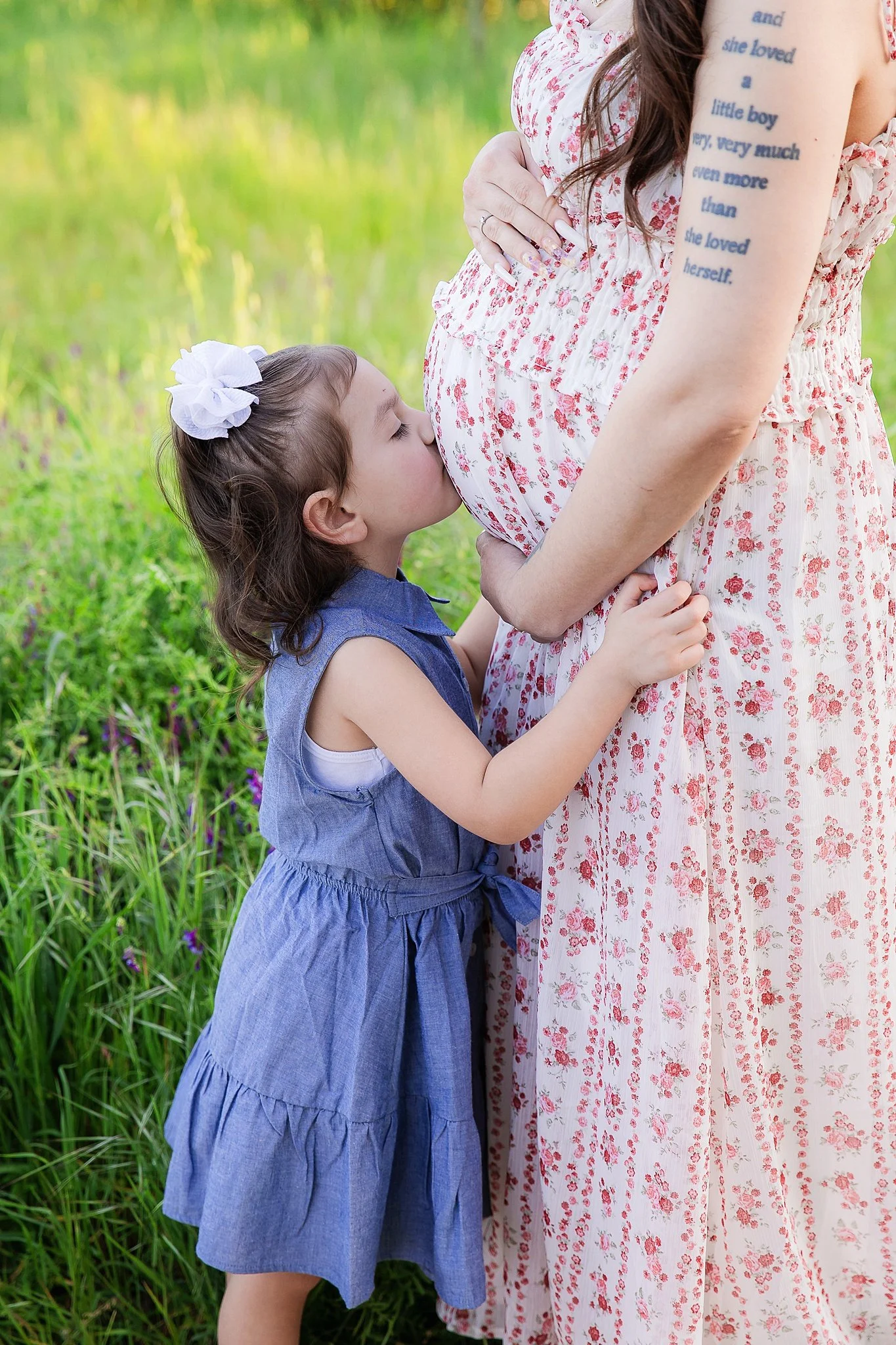 Sweet maternity photo of a young child kissing her mother’s baby bump during an outdoor maternity session in Elk Grove, California