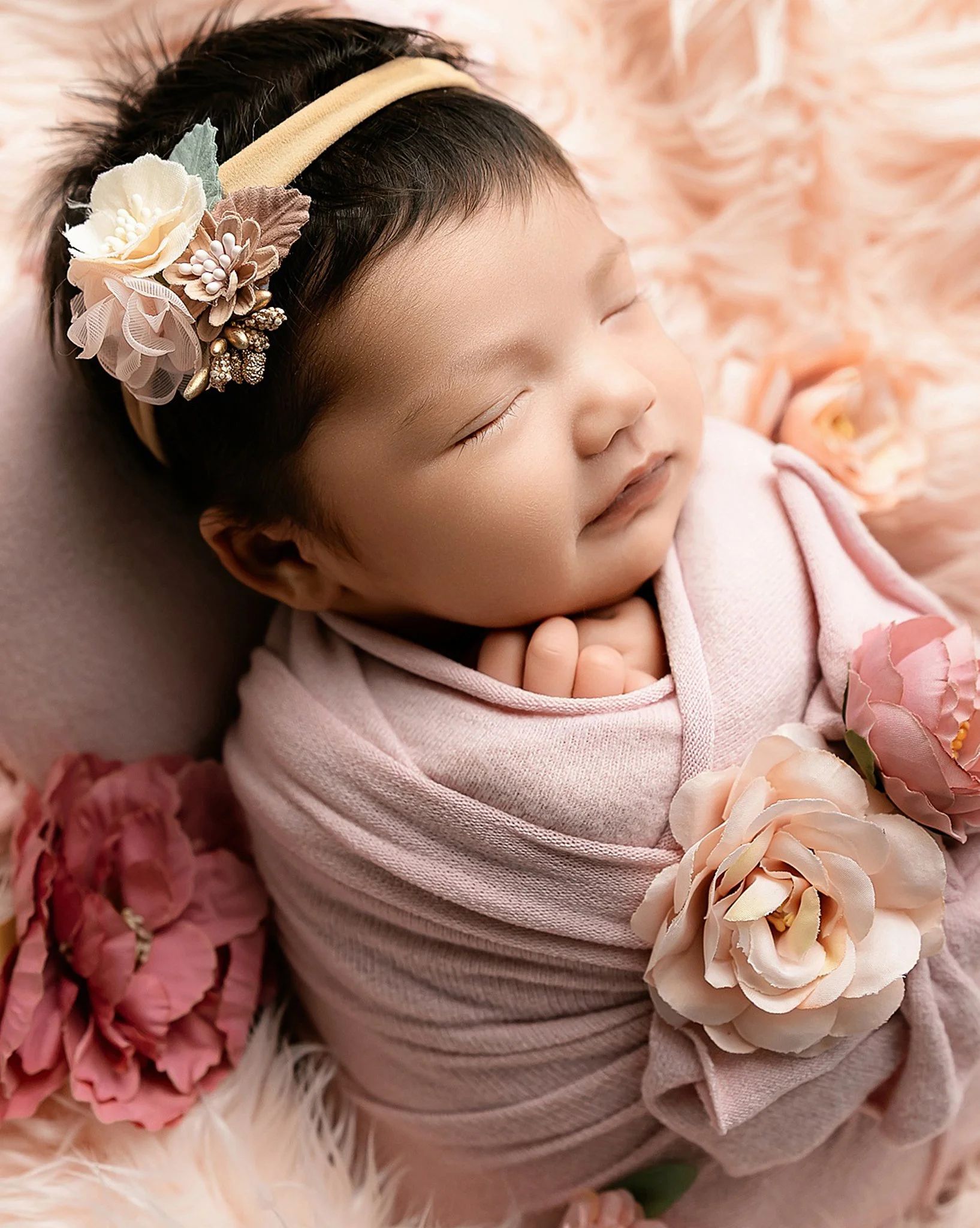 Newborn baby girl peacefully sleeping during a studio newborn photography session with soft pink florals in Elk Grove, California