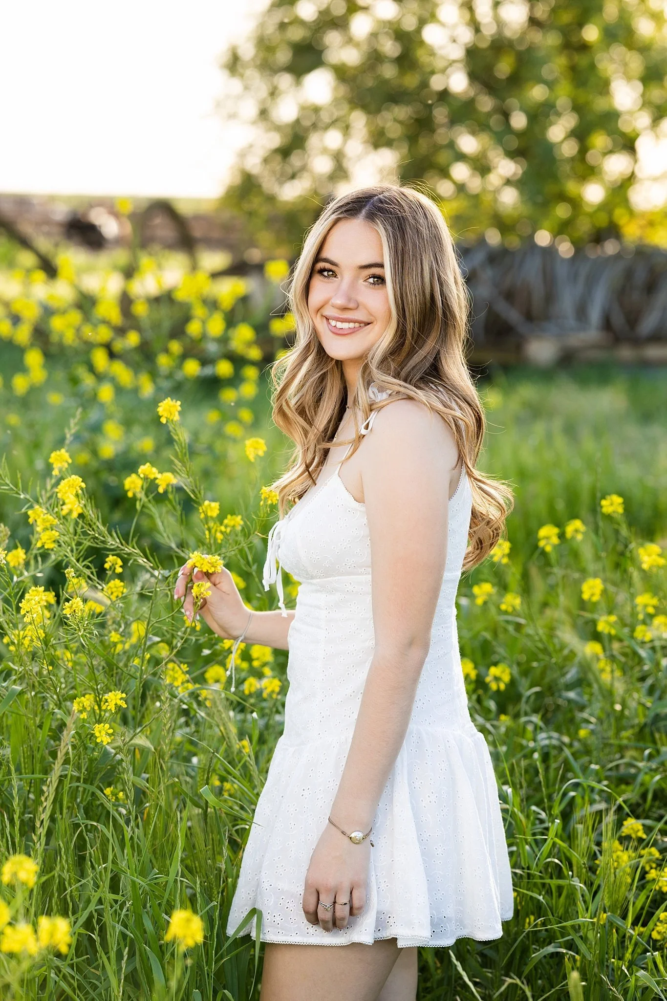 High school senior smiling during a golden hour outdoor senior portrait session in a wildflower field near Elk Grove, California