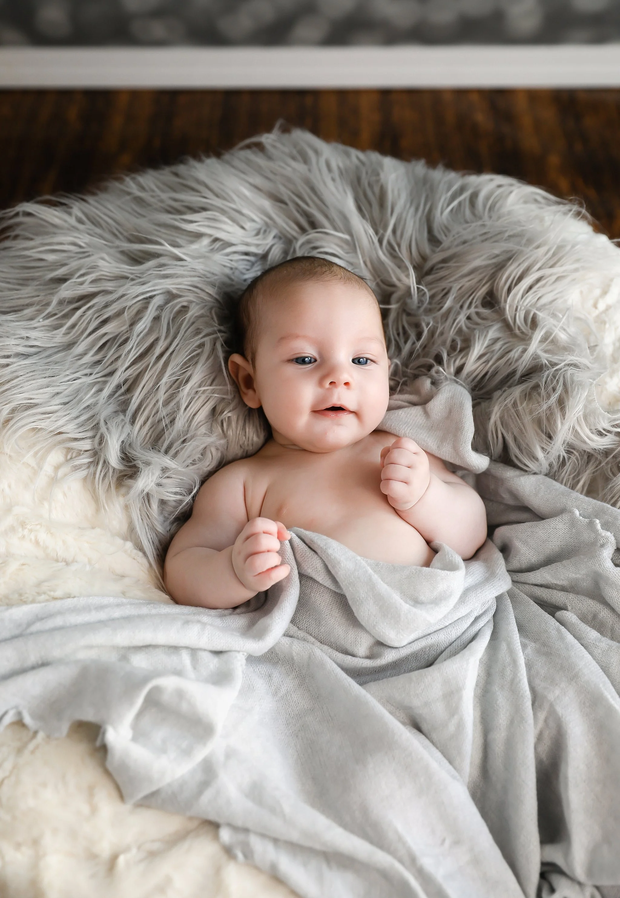 Smiling three-month-old baby laying on a fur background during a studio milestone portrait session in Elk Grove, California