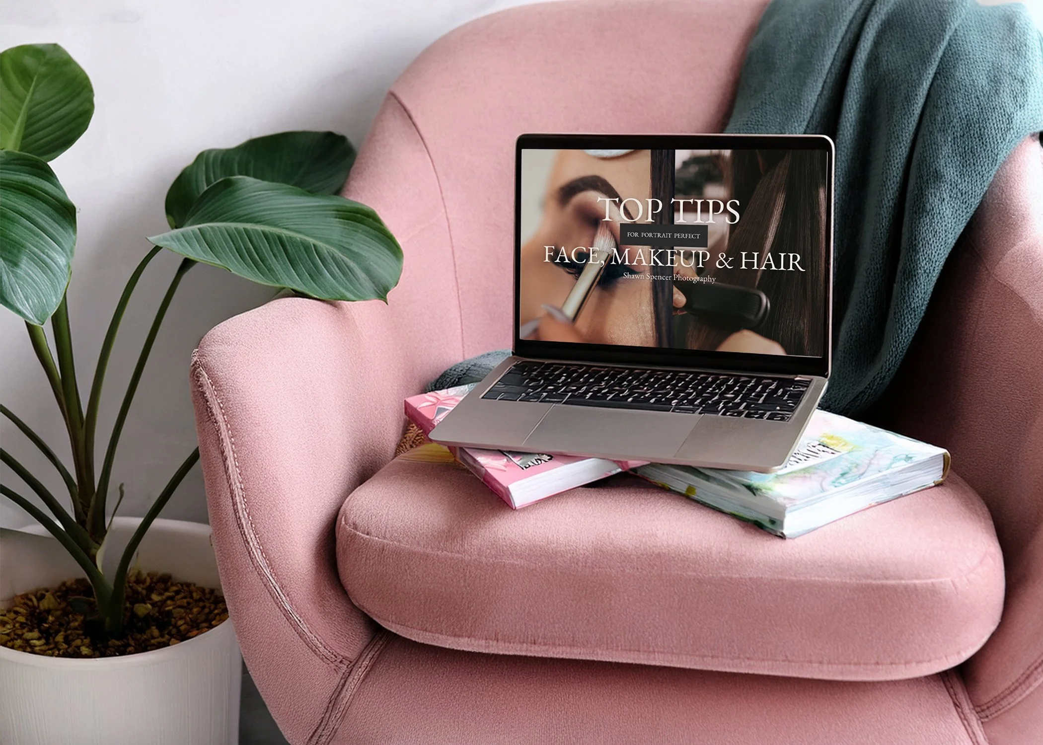 A laptop displaying a senior face, makeup, and hair guide resting on a pink chair with books and soft decor.