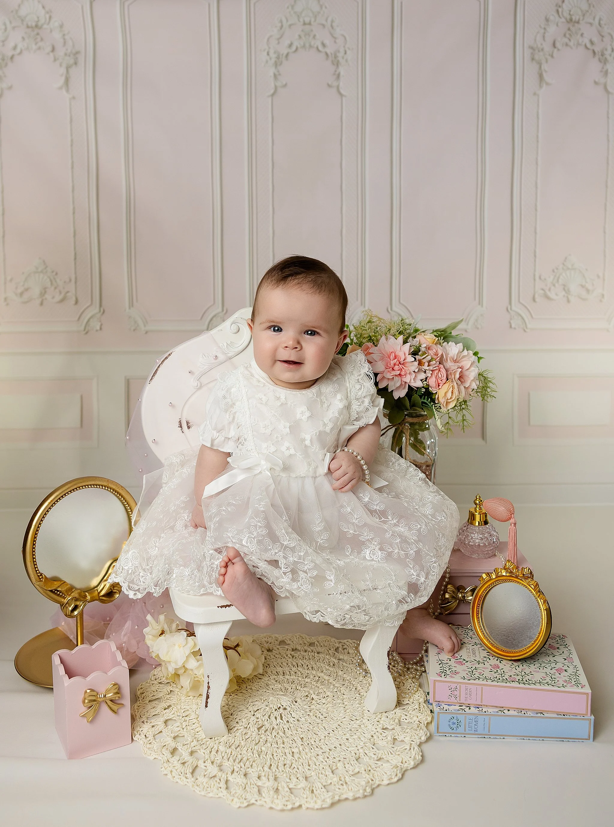 Six-month-old baby girl sitting in a vintage chair during a studio milestone photography session in Elk Grove, California.