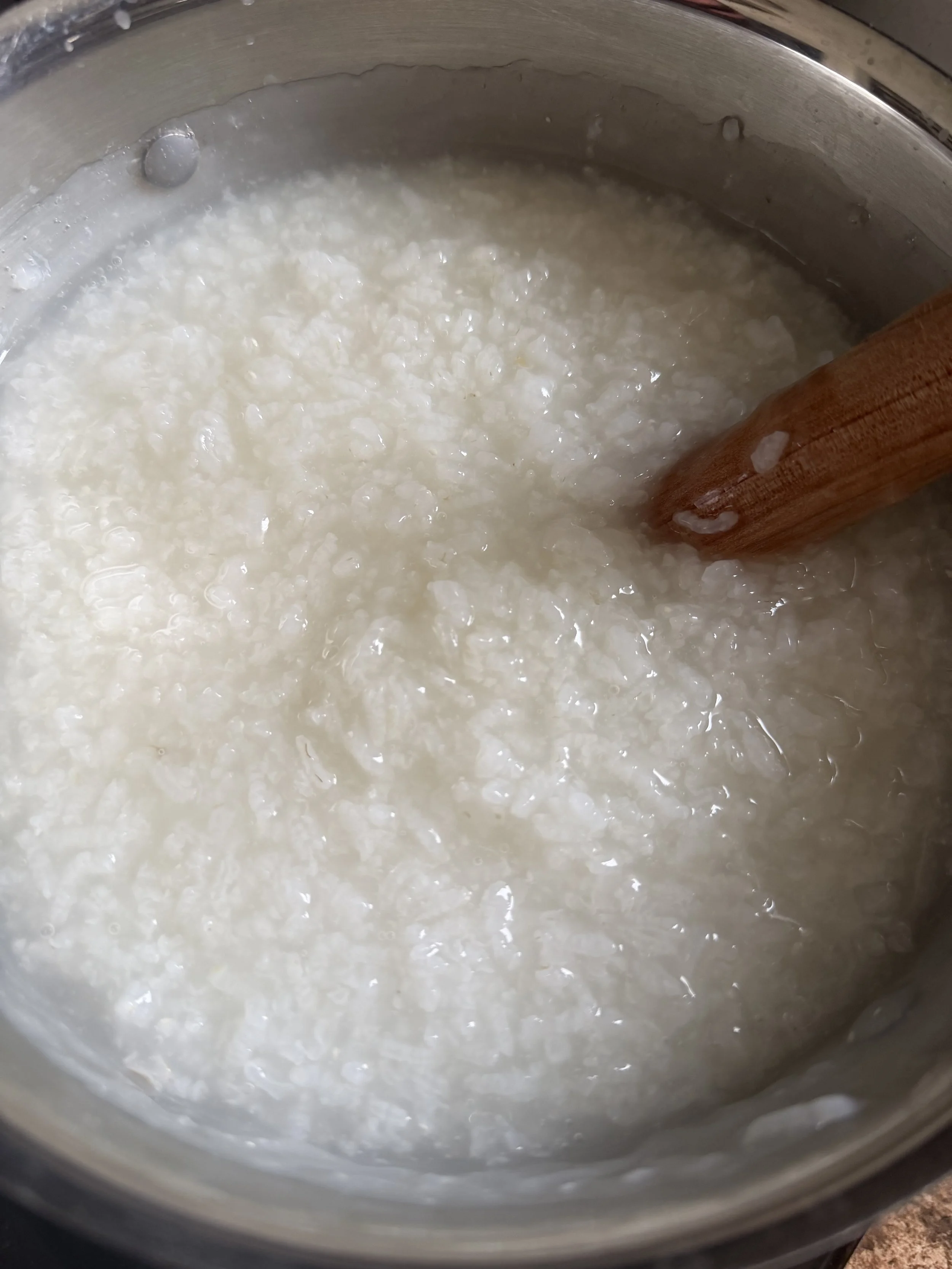 Large pot of simmering organic Korean white rice porridge with milky starchy broth texture
