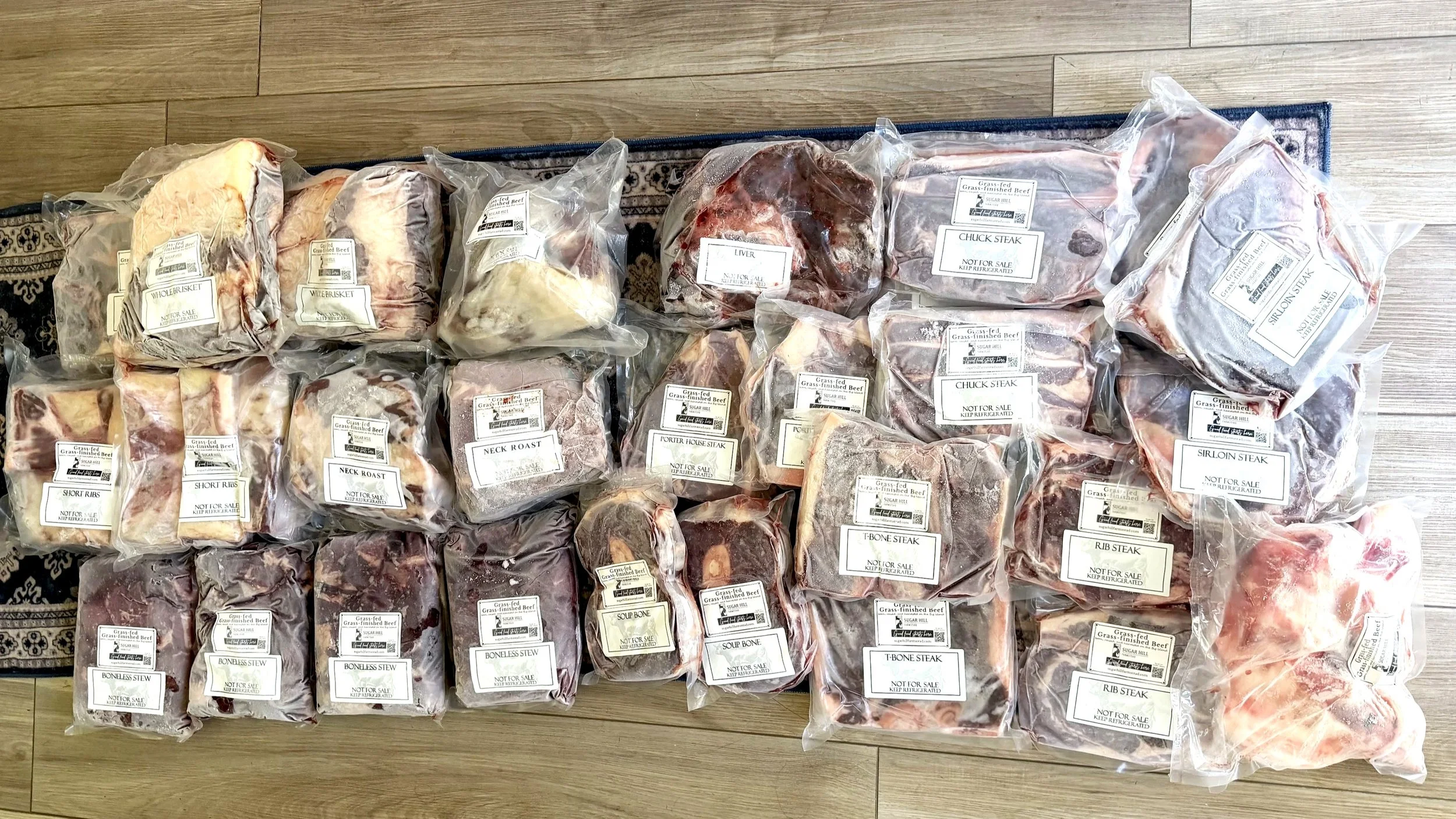 1/4 grass-fed and grass-finished cow share laid out on the floor showing steaks, roasts, ground beef, bones, stew meat, and organ meats from a Hawaii local farm.