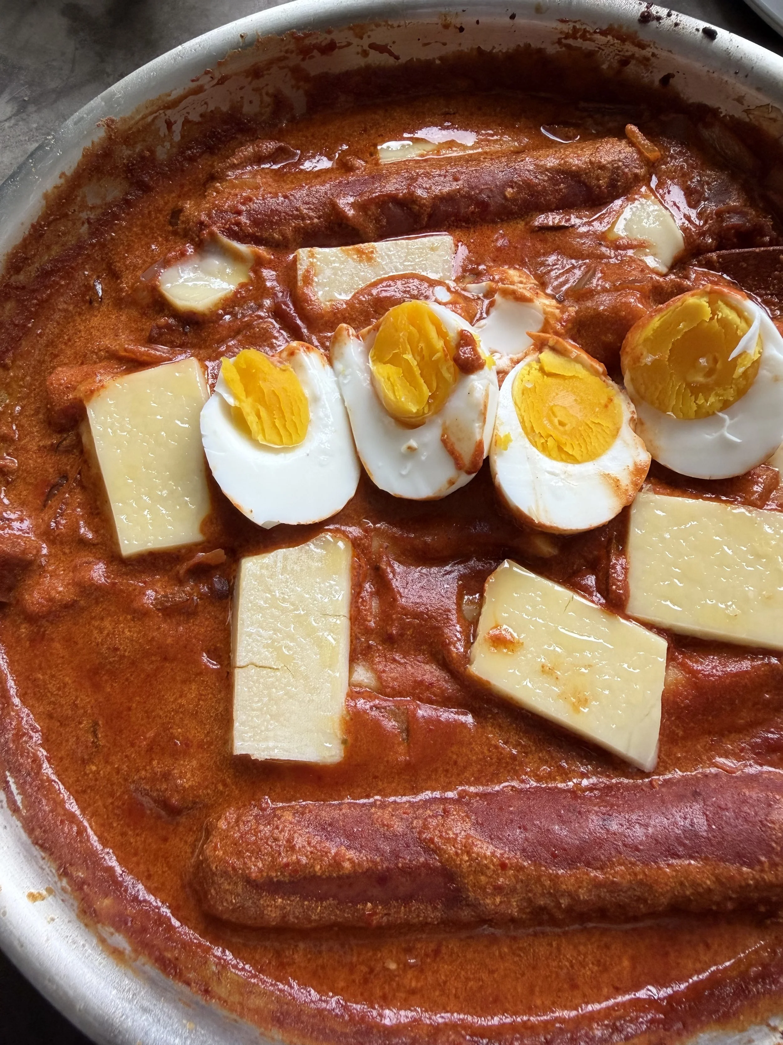 Creamy rosé tteokbokki with chewy rice cakes, bright egg yolks, crispy prosciutto, and melted raw cheese
